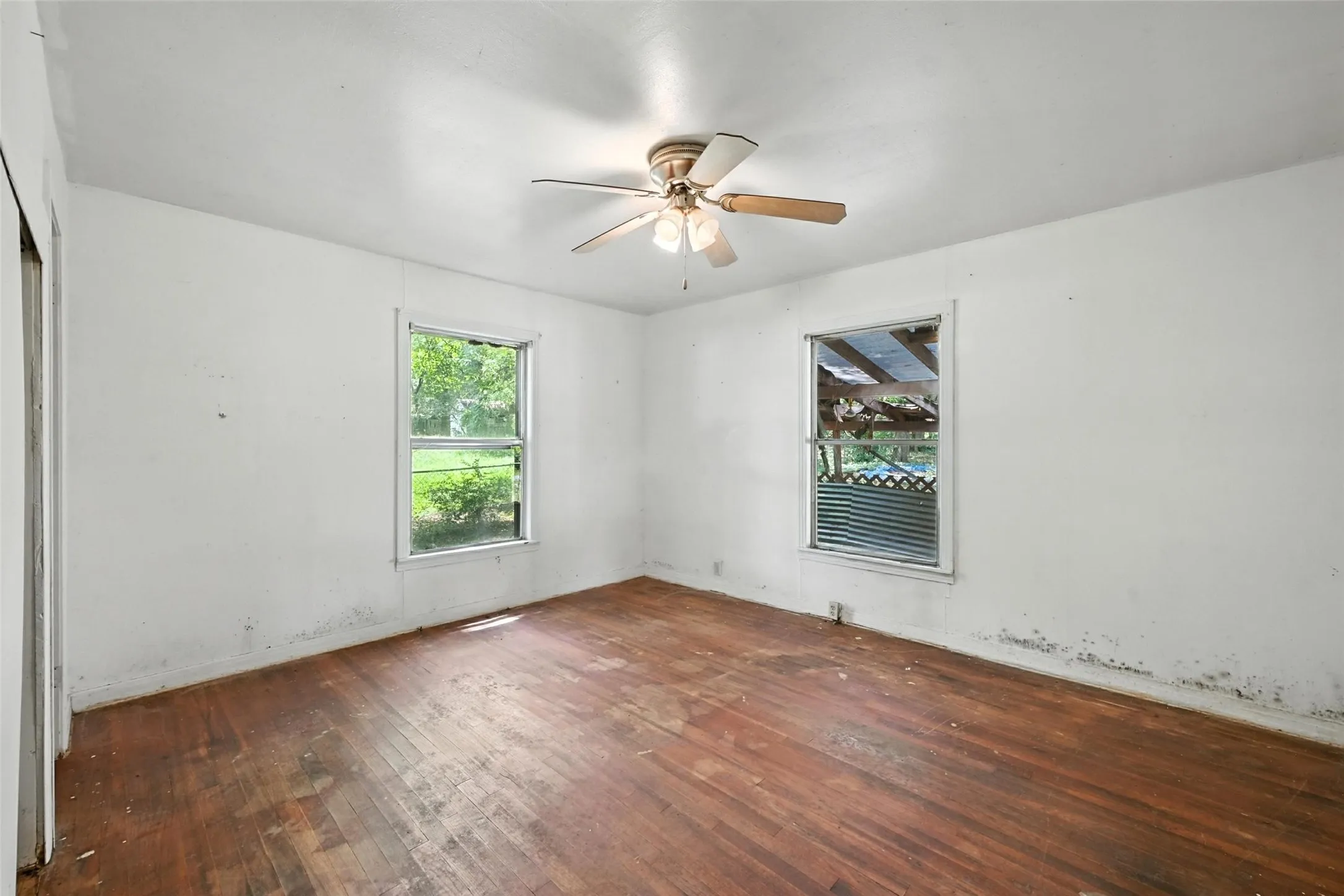 Empty room featuring dark wood-style floors, healthy amount of natural light, and ceiling fan