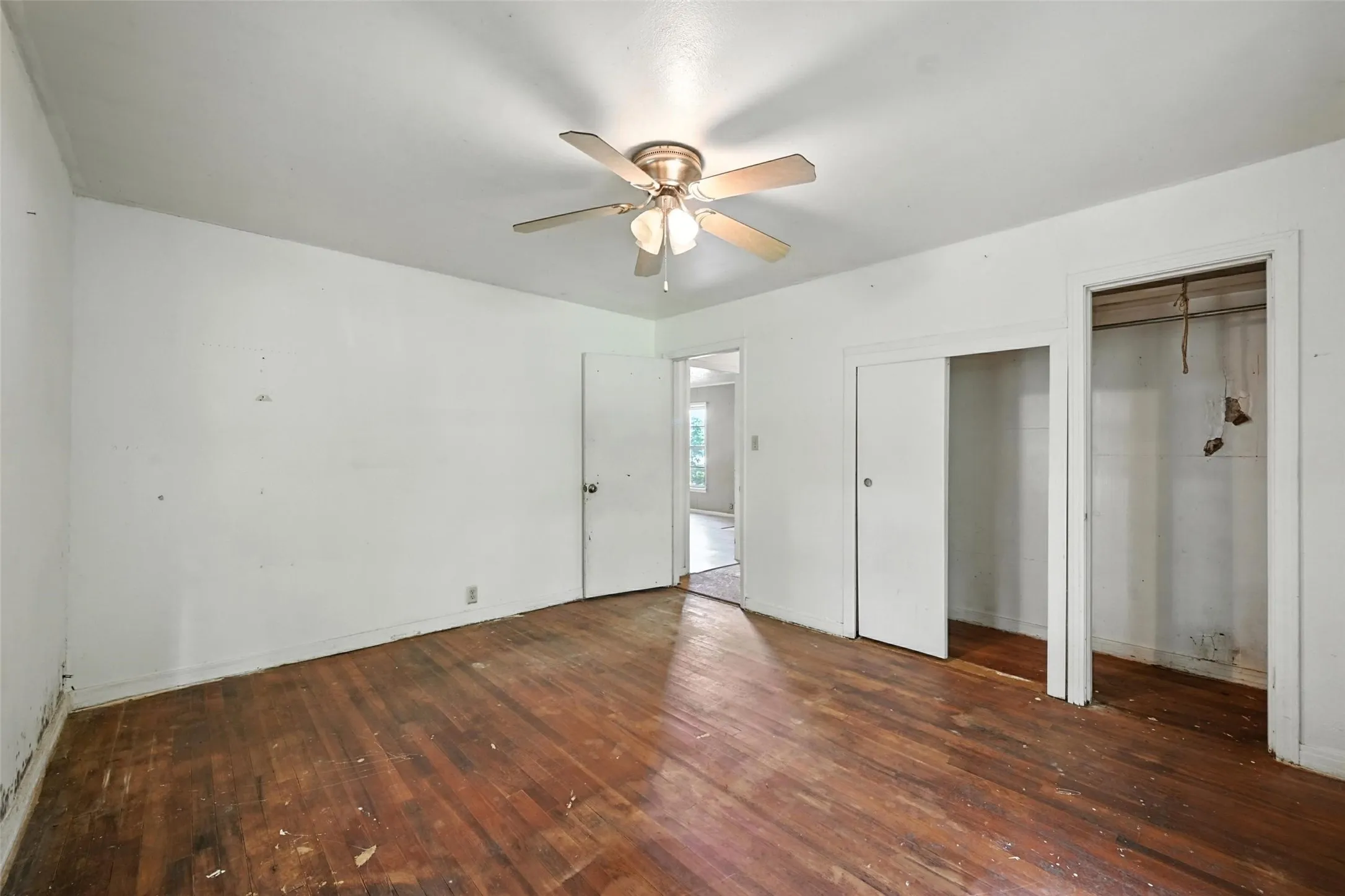 Unfurnished bedroom with multiple closets, dark wood-style floors, and ceiling fan