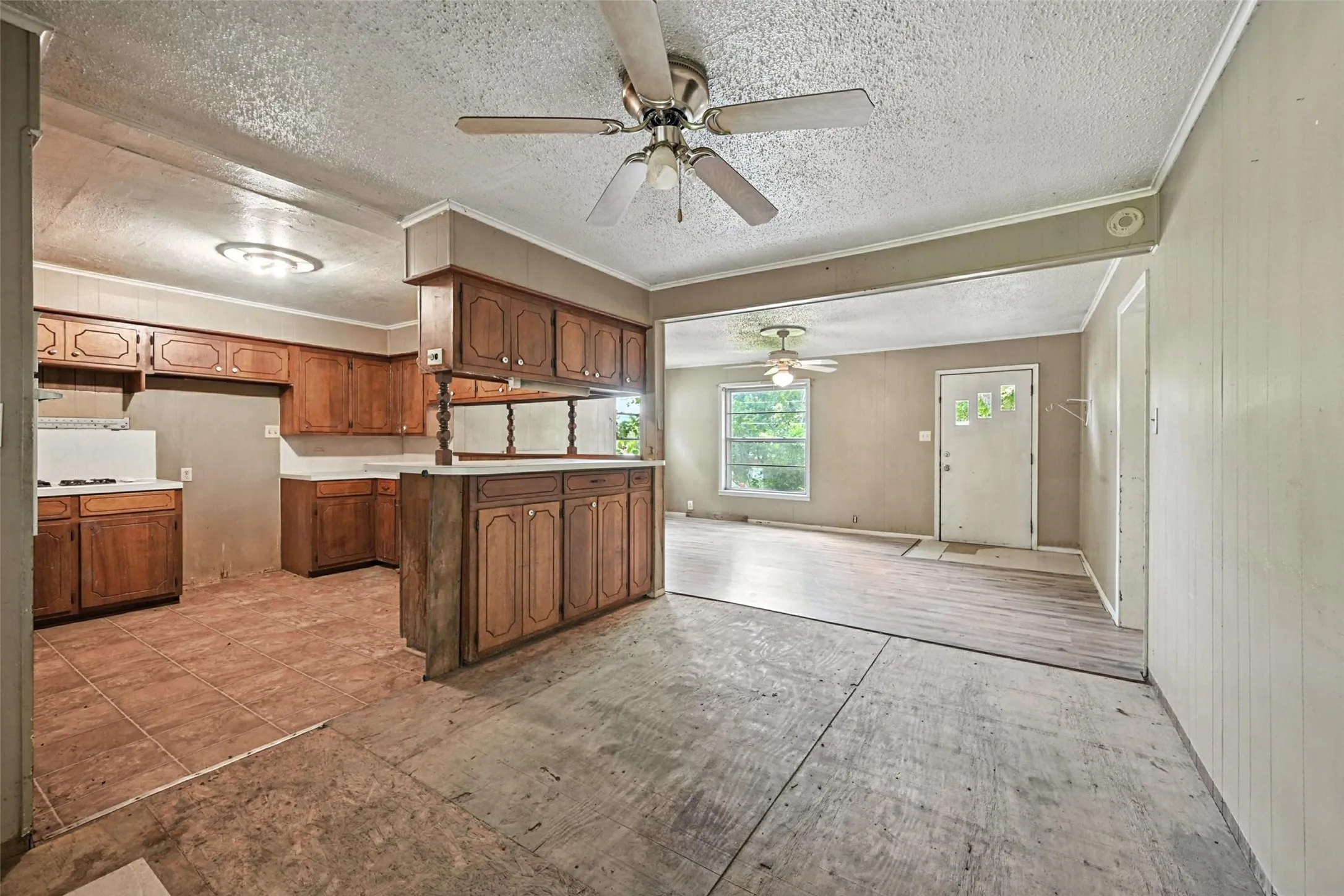 Kitchen with wood finish cabinetry, light countertops, open floor plan, a peninsula, and ceiling fan