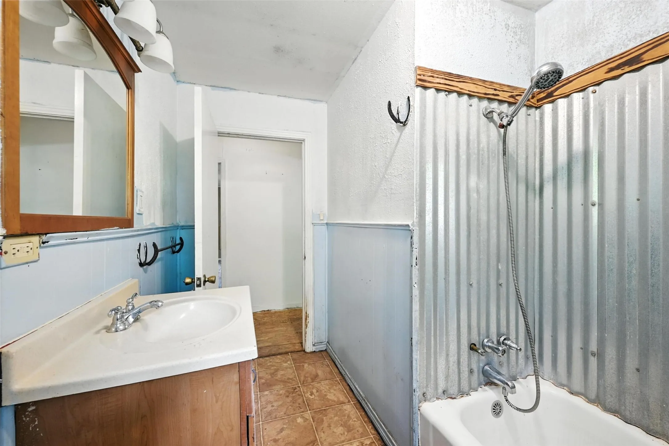 Full bath featuring vanity, shower / bathtub combination with curtain, a textured wall, and light tile patterned floors