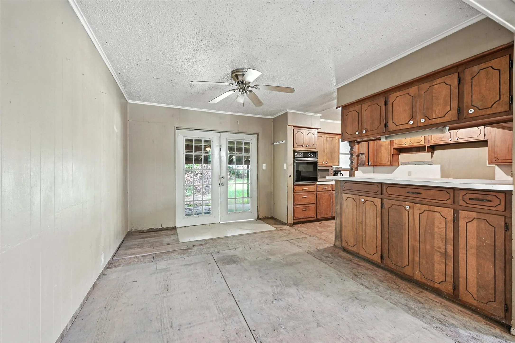 Kitchen featuring french doors, light countertops, wood finish cabinets, black oven, and ornamental molding