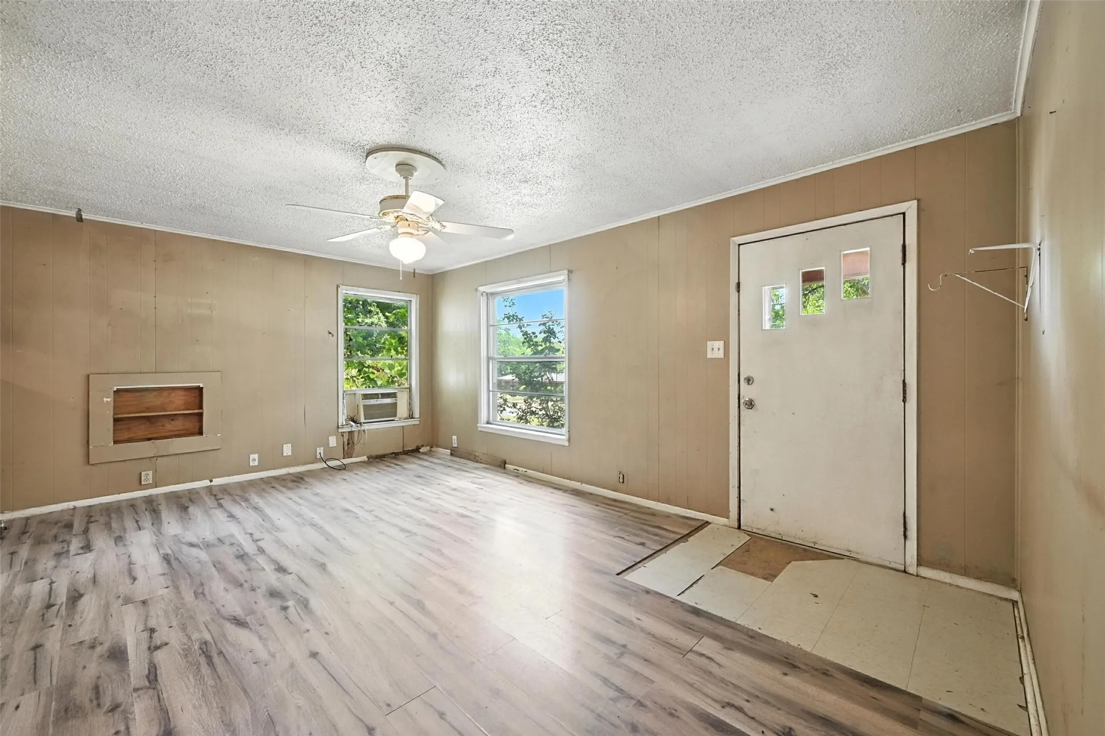 Entryway featuring light wood-style flooring, a textured ceiling, wood walls, and a ceiling fan