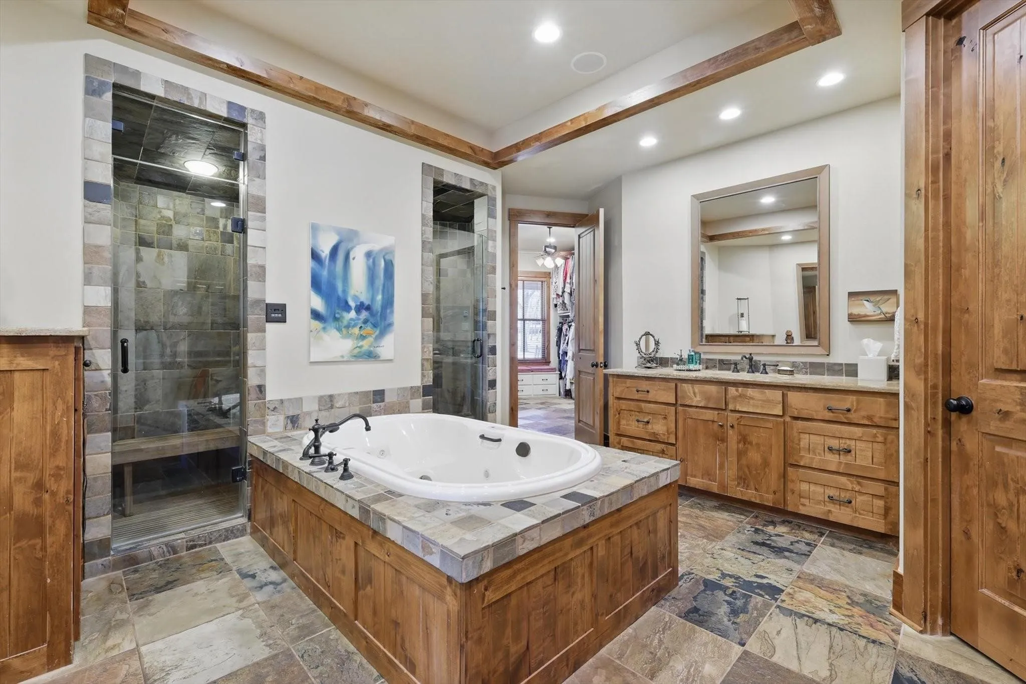 Full bath with shower stall, vanity, jetted tub, tray ceiling, and recessed lighting.