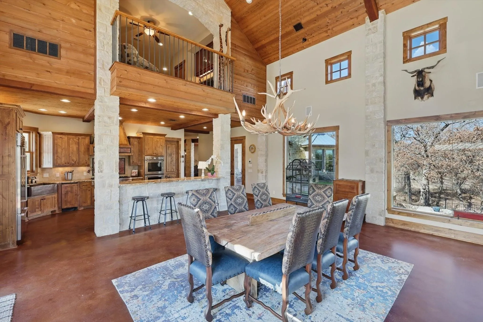 Dining area featuring vaulted ceiling, finished concrete floors, wood ceiling with exposed beams, fireplace, and recessed lighting.
