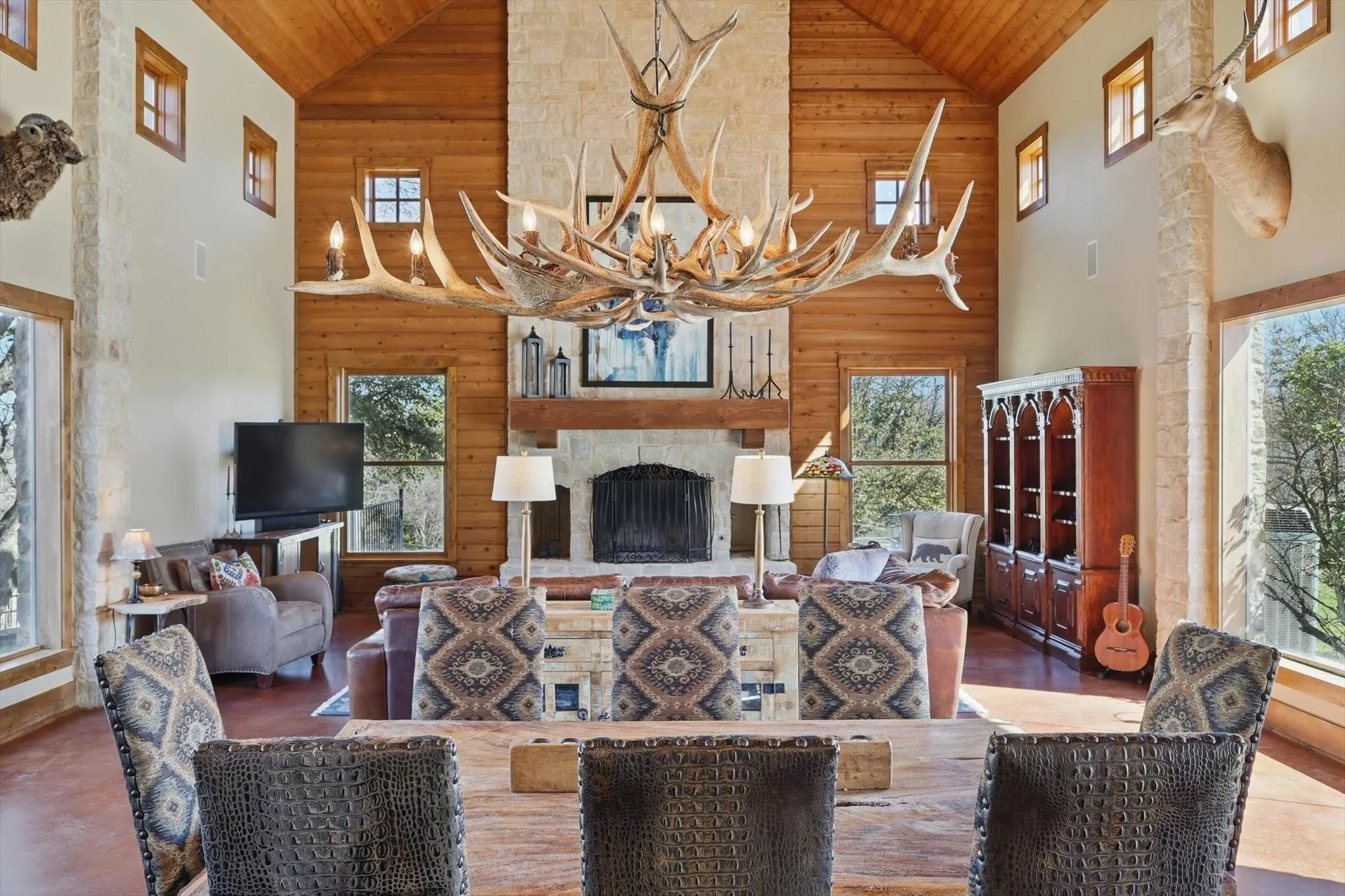 Dining area featuring vaulted ceiling, finished concrete floors, wood ceiling with exposed beams, fireplace, and recessed lighting.