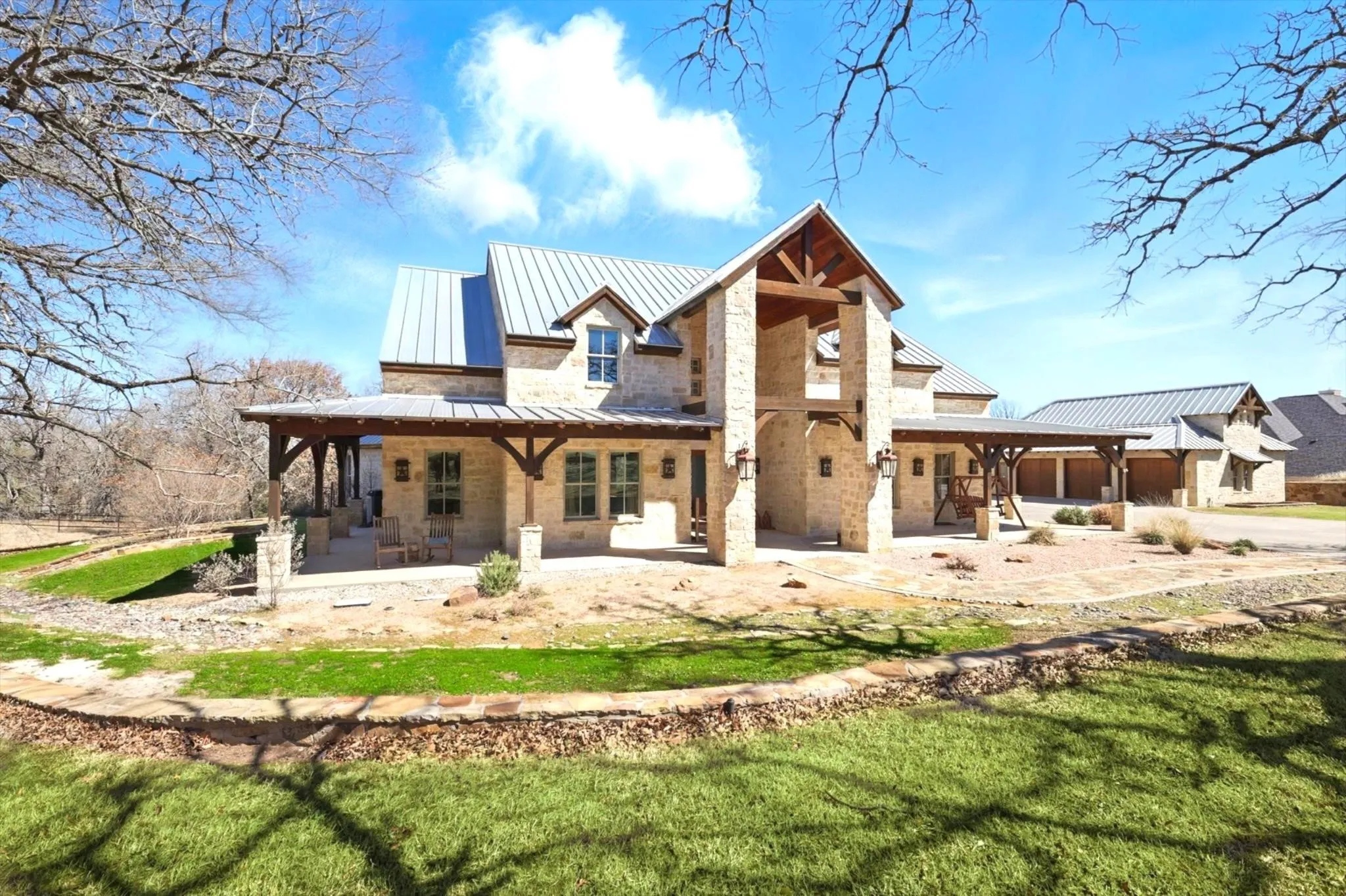 Rear exterior view featuring standing seam metal roof, lawn, and stone siding.