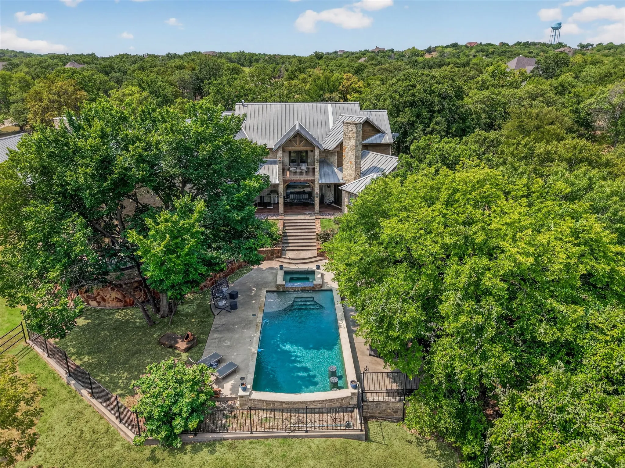 Swimming pool with stair entry, patio space, and connected hot tub.