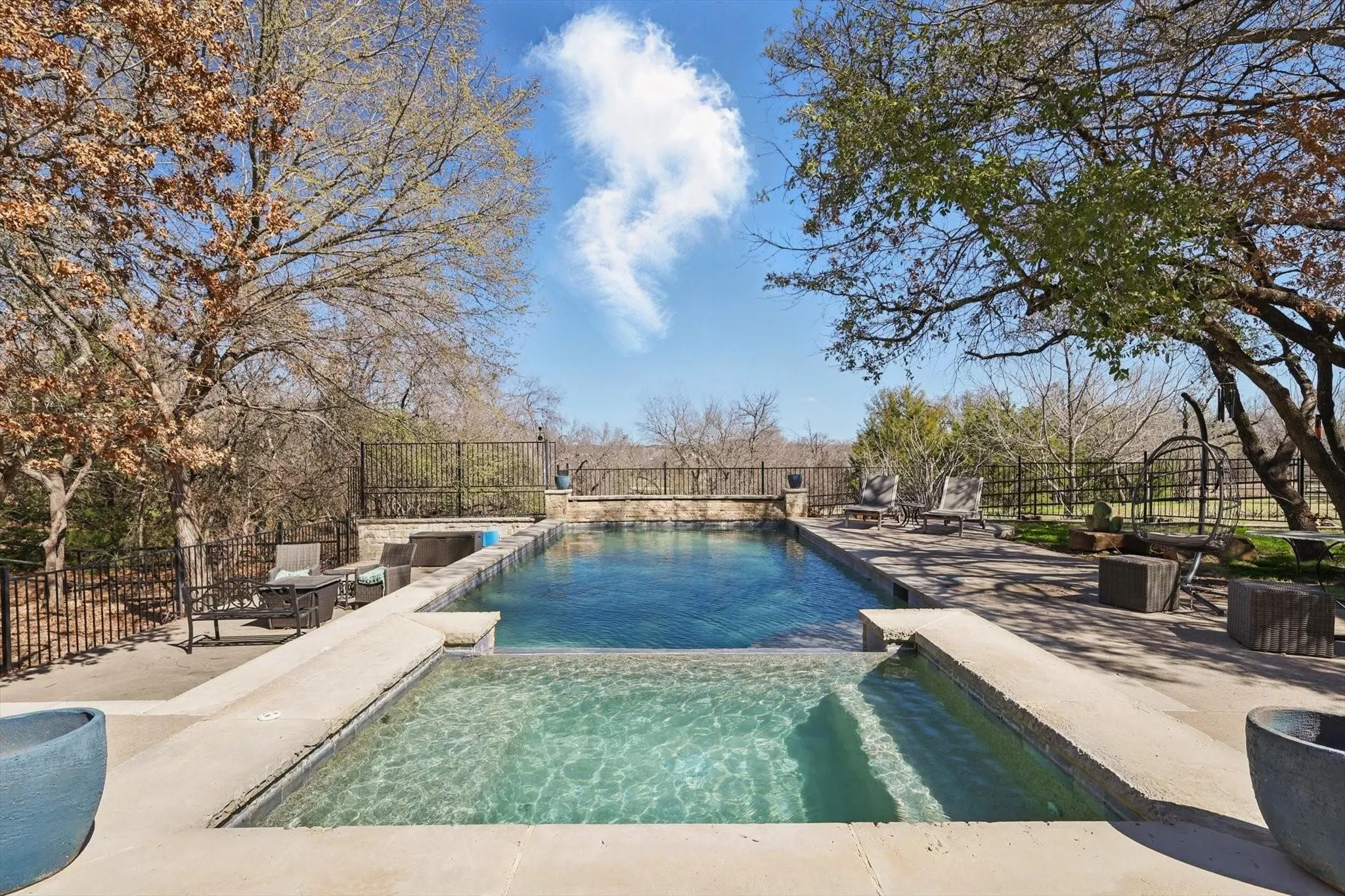 Pool area with patio and connected hot tub.