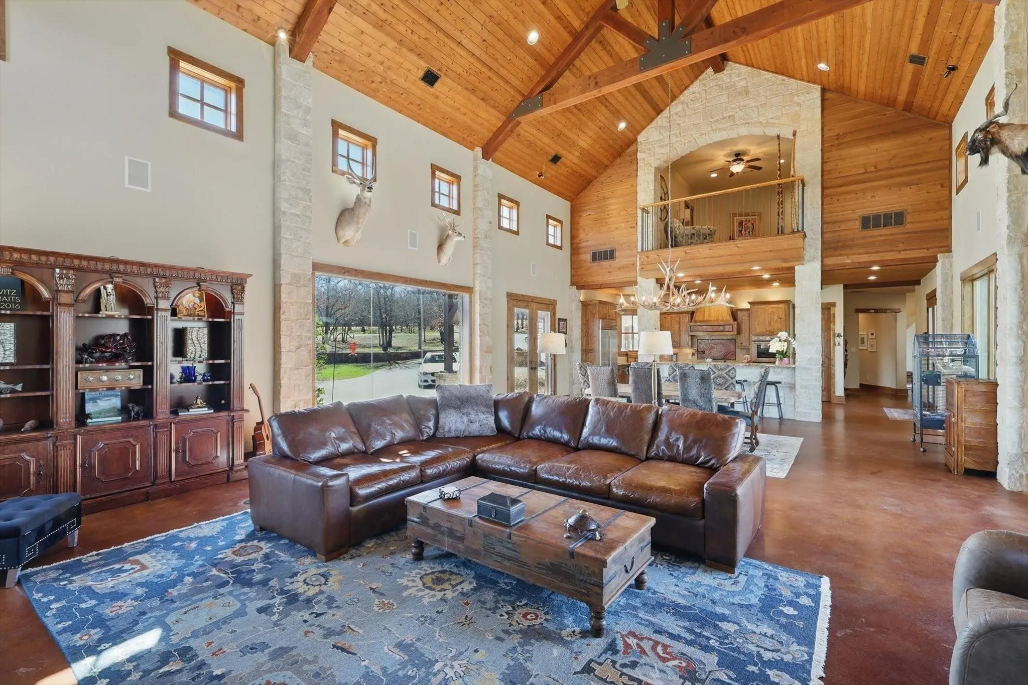 Living room with wood ceiling and exposed beams, concrete flooring, vaulted ceiling, ceiling fan, and abundant natural light.