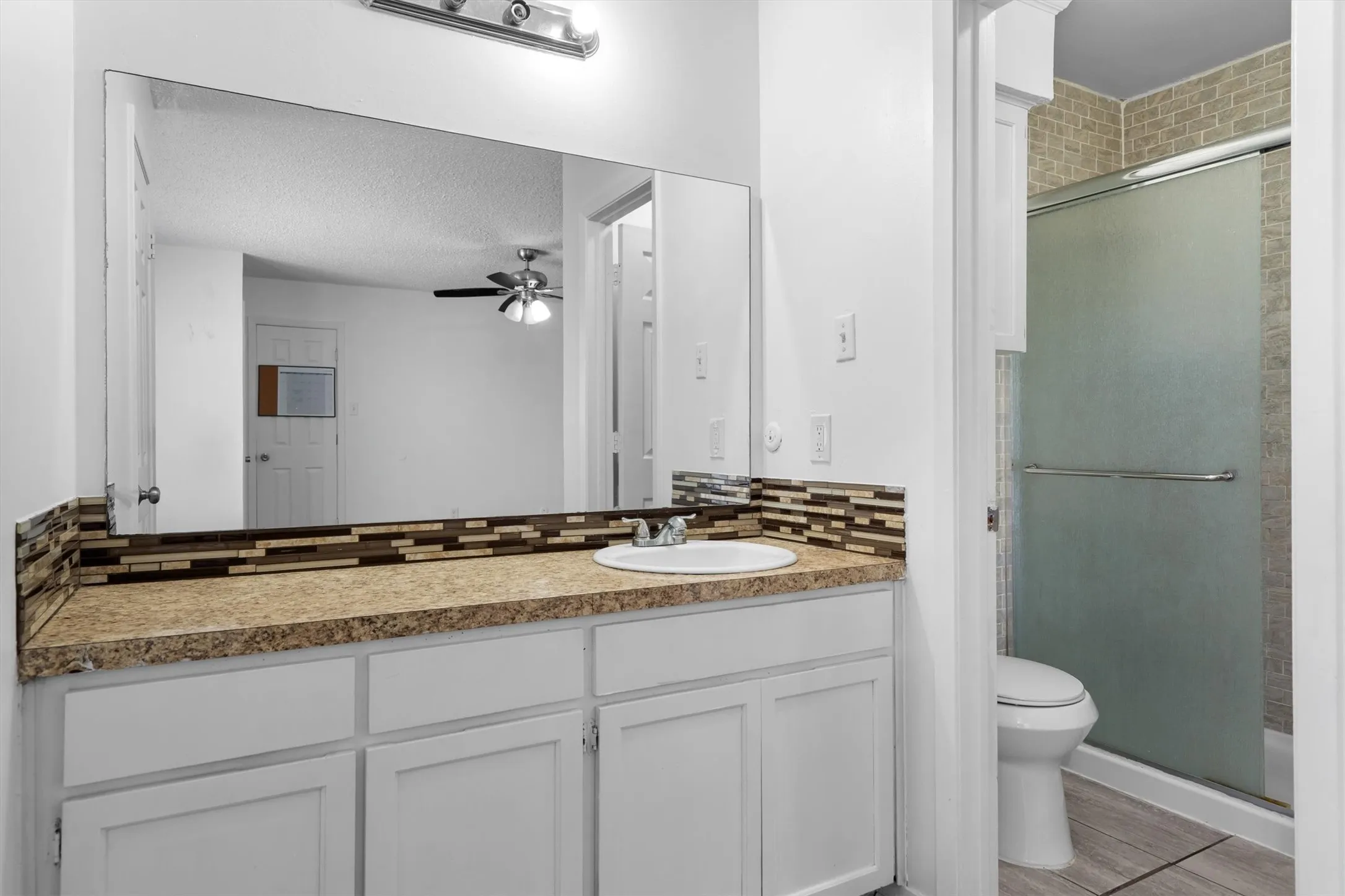 Bathroom vanity with an integrated sink, a rectangular mirror, and a tile backsplash