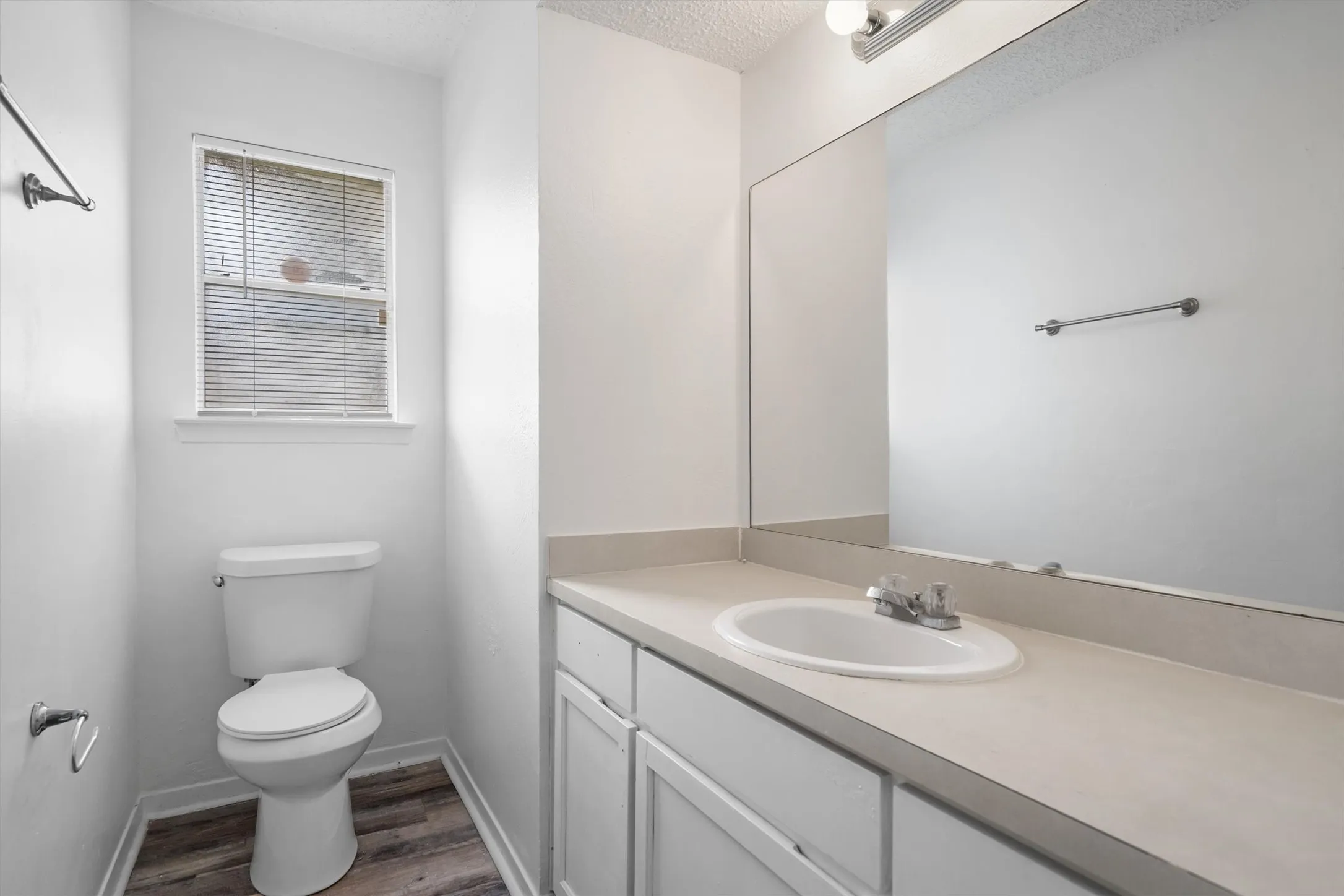 Vanity with integrated sink, chrome faucet, and a large wall-mounted mirror