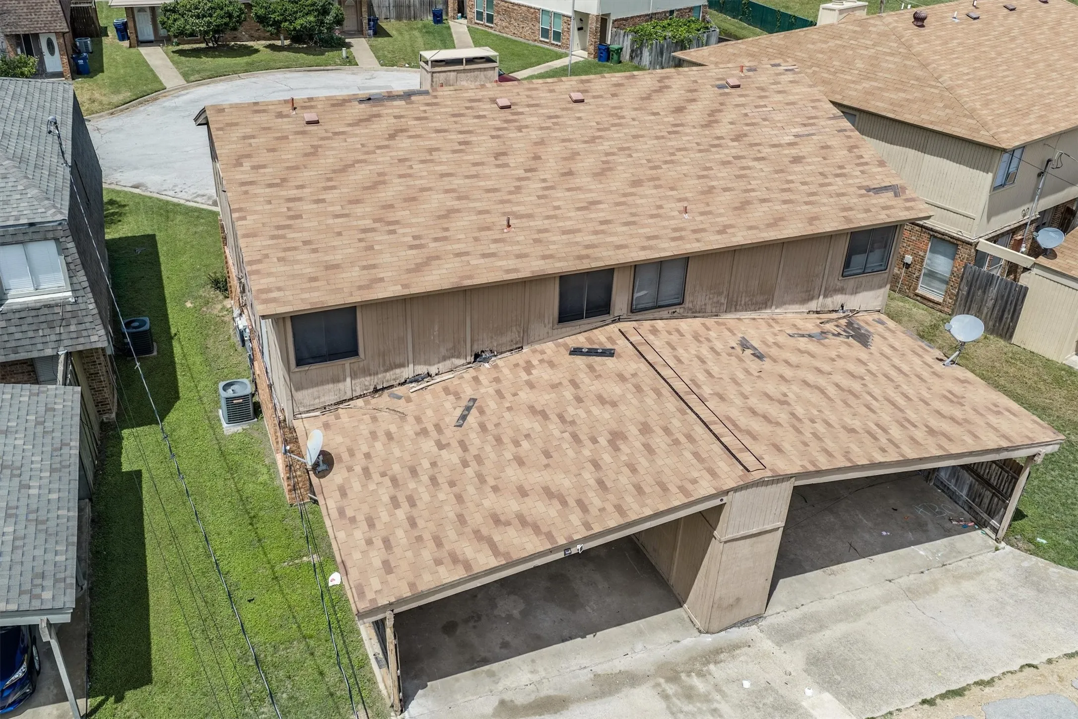 Two-story property with a brown shingle roof, vertical siding, and a two-vehicle carport