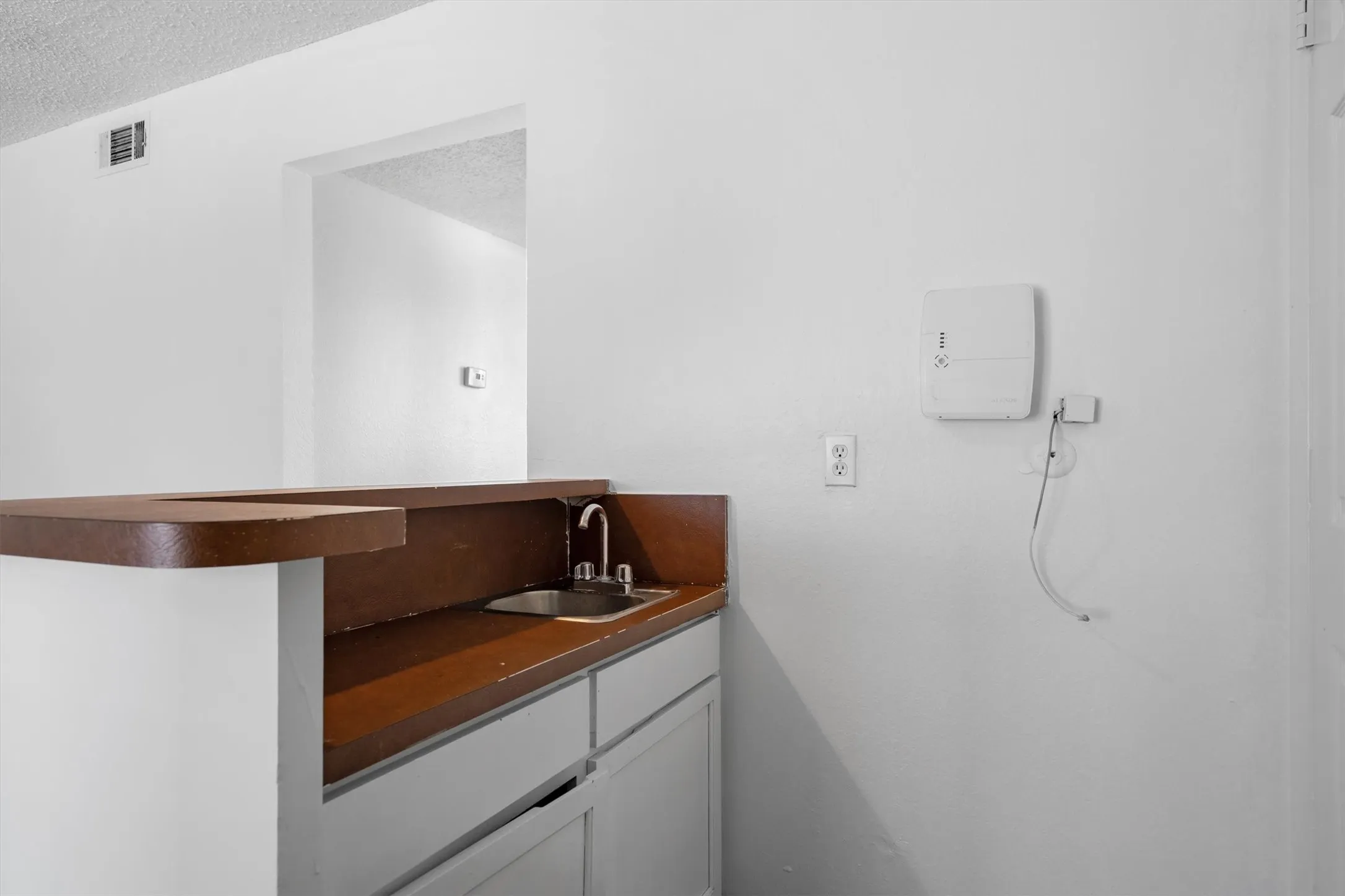 Built-in bar with a stainless steel sink, chrome faucet, and wood-finish countertop