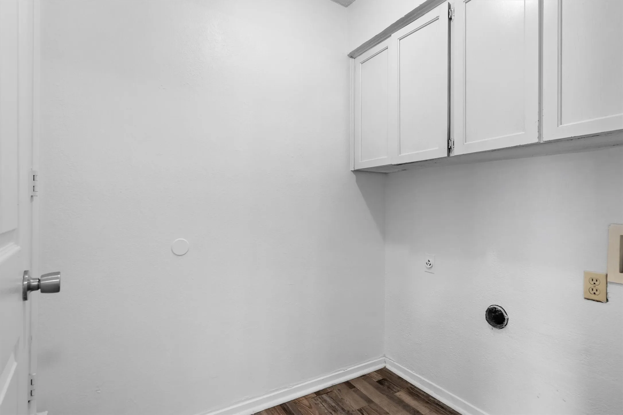 White shaker-style cabinetry, wood-finish flooring, and white walls