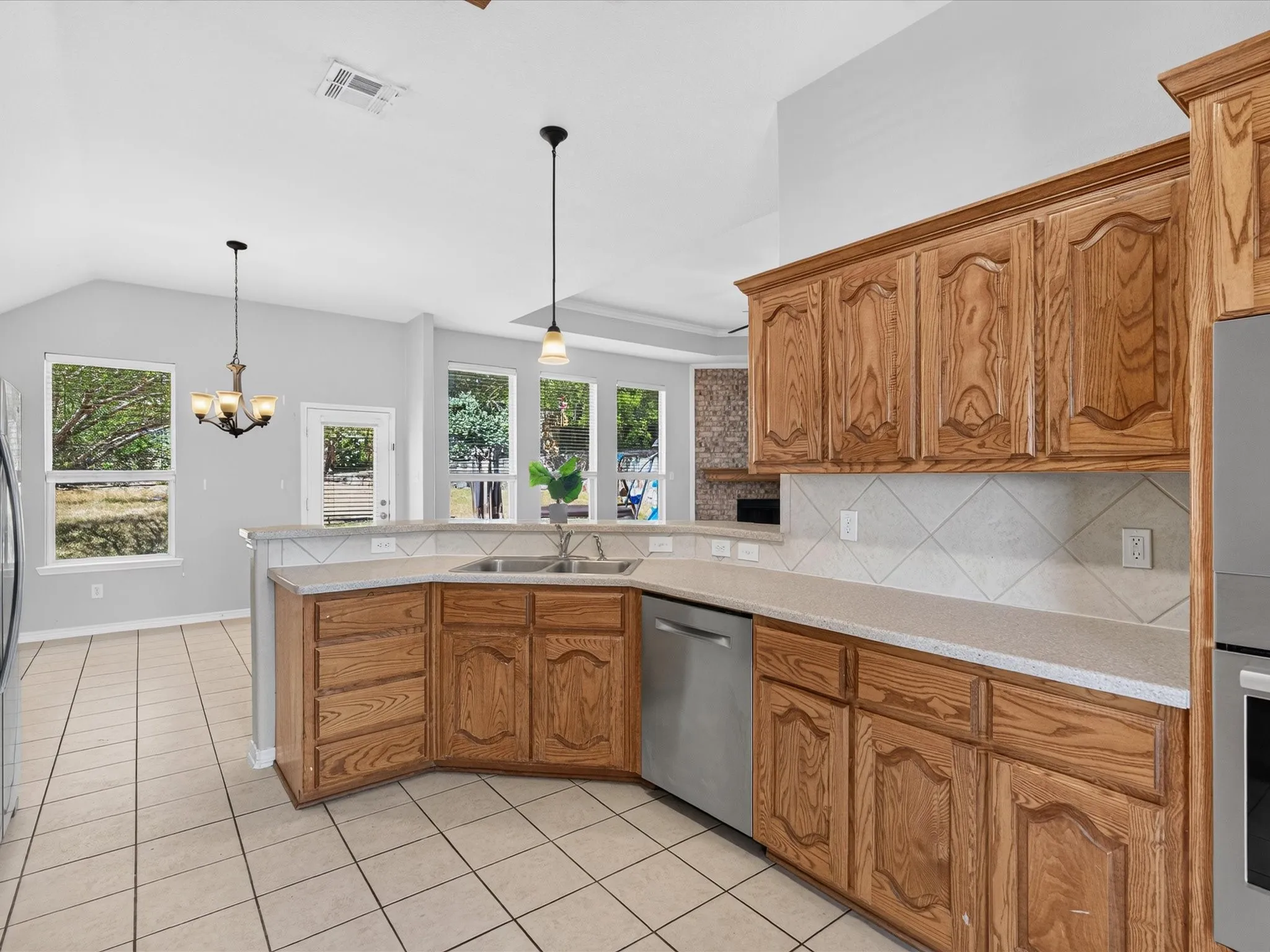 Kitchen featuring wood cabinetry, light countertops, stainless steel dishwasher, tile flooring, and recessed lighting