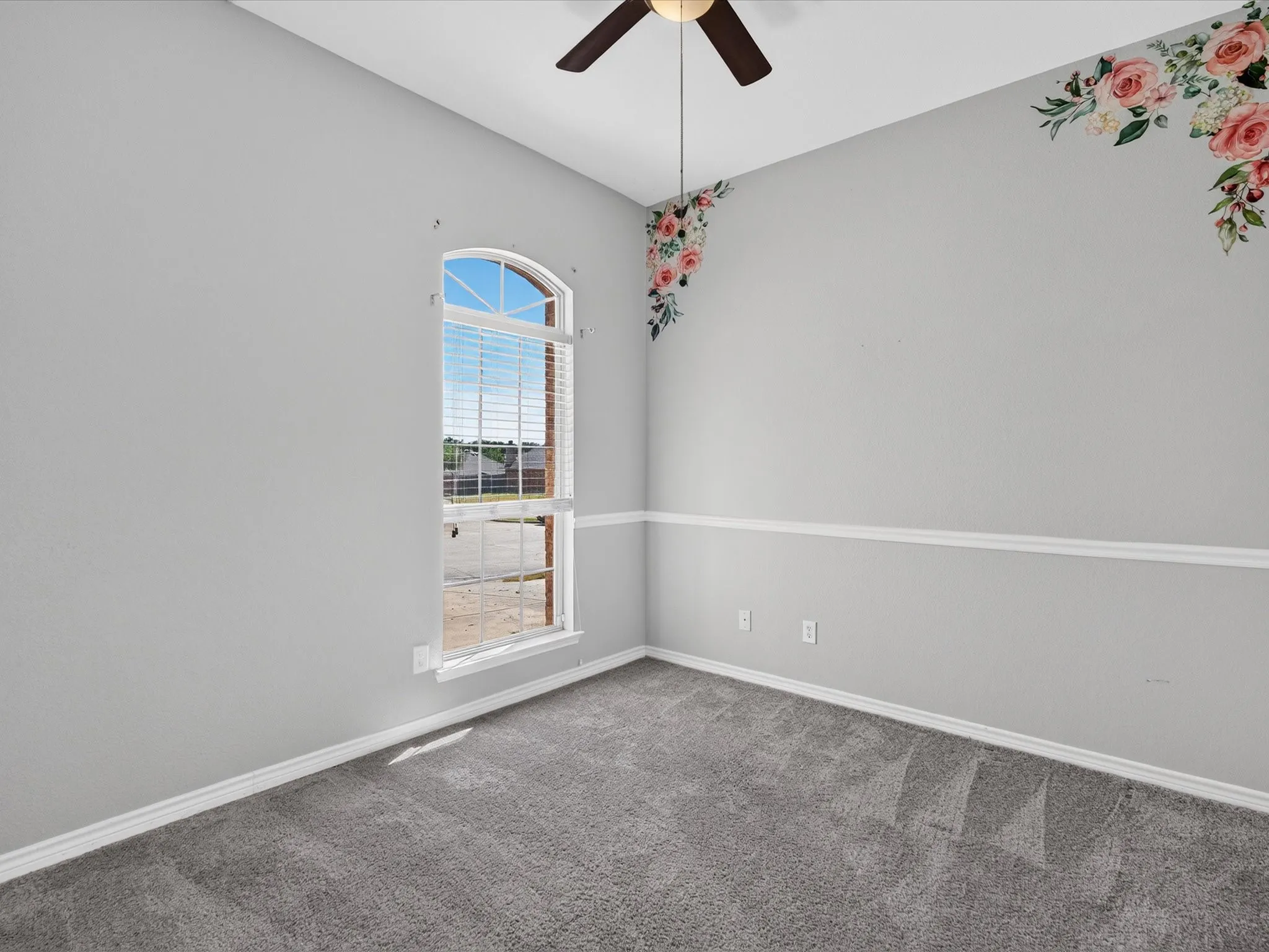 Arched window with blinds, ceiling fan, carpeted flooring, and wall trim