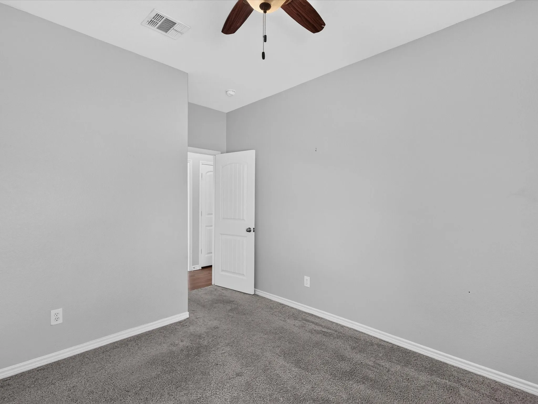 Light gray wall paint, dark gray carpeting, white trim, and a ceiling fan with wood-look blades