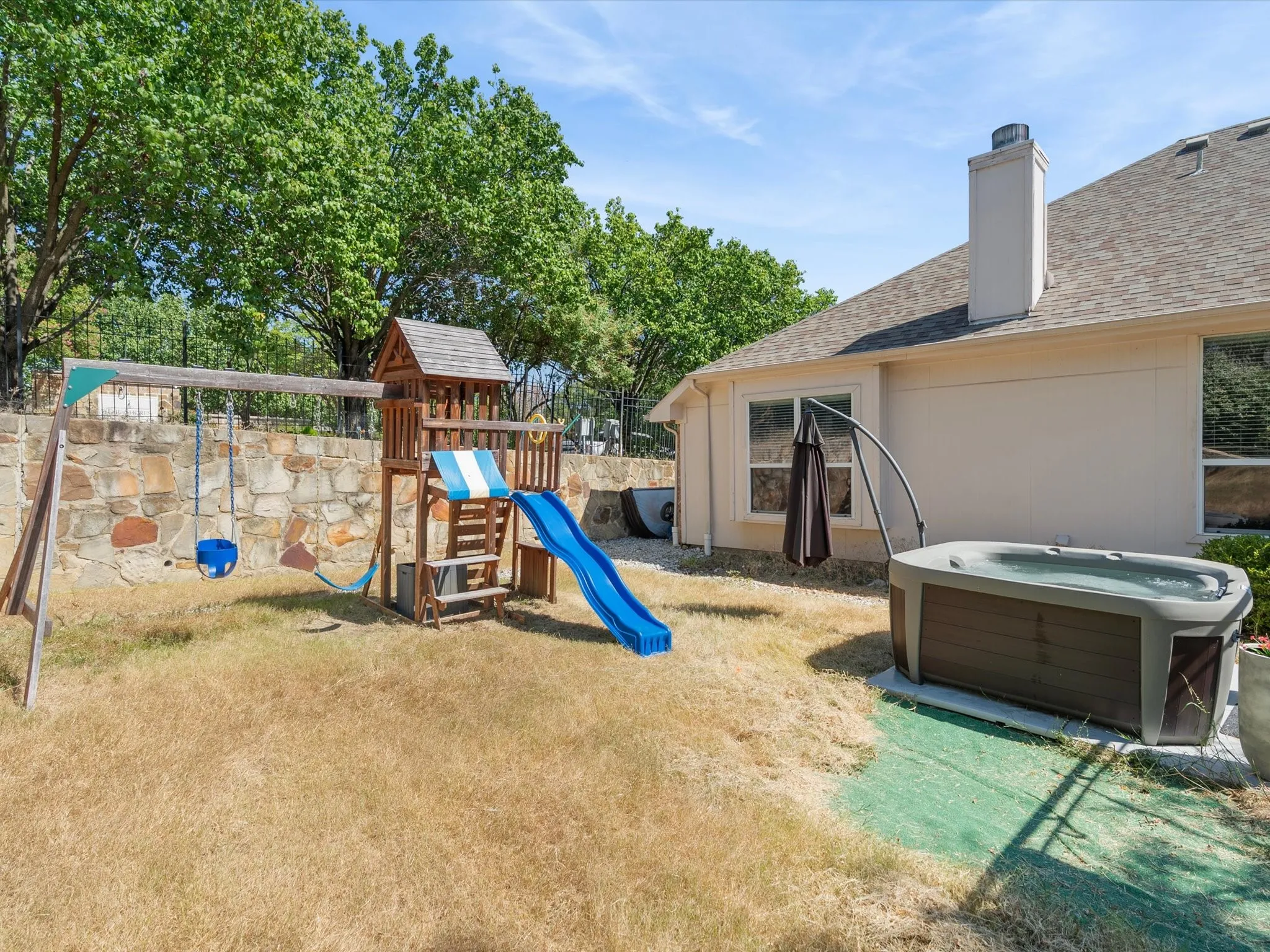 Outdoor spa, stone retaining wall, and mature trees