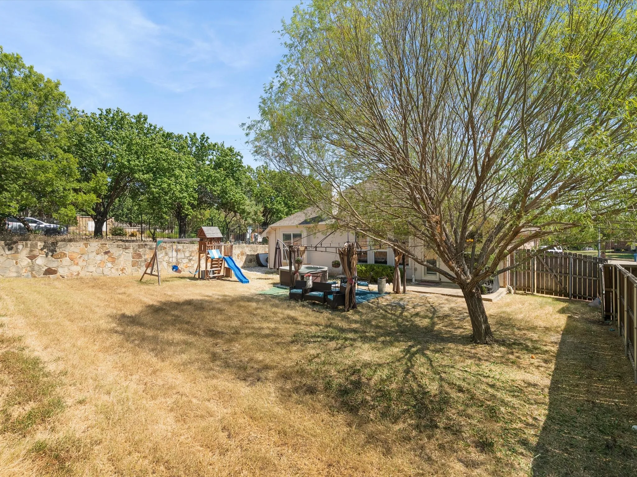 Spacious backyard featuring a stone retaining wall and a privacy fence