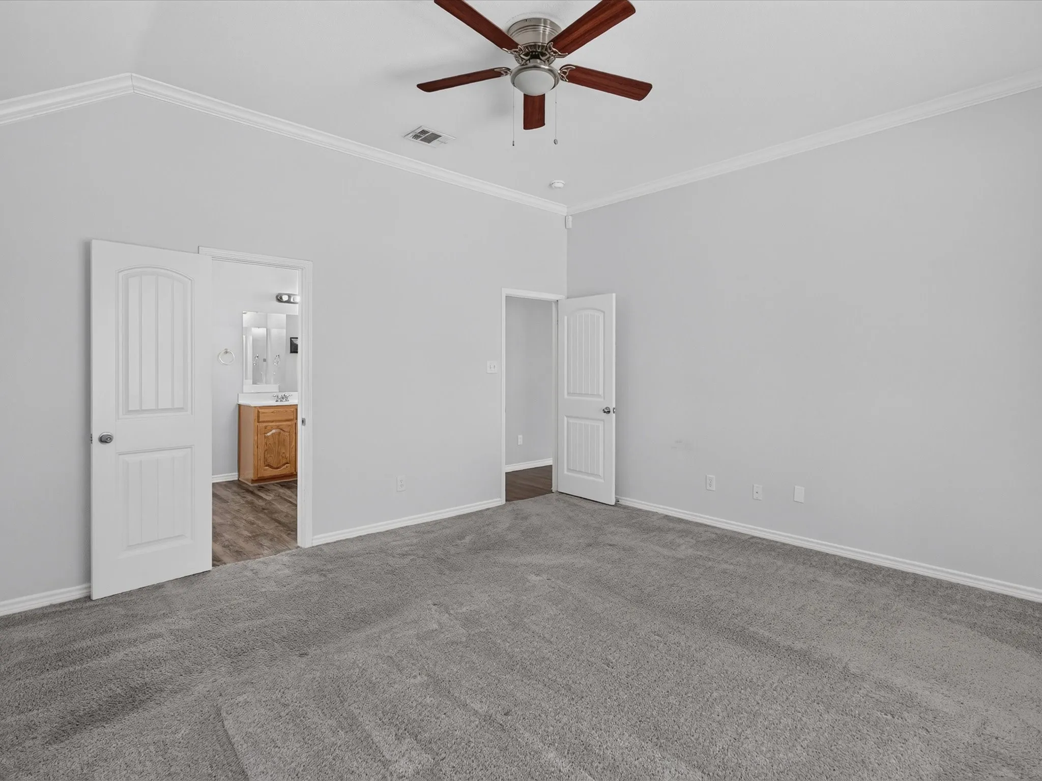 Vaulted ceiling with crown molding and a ceiling fan