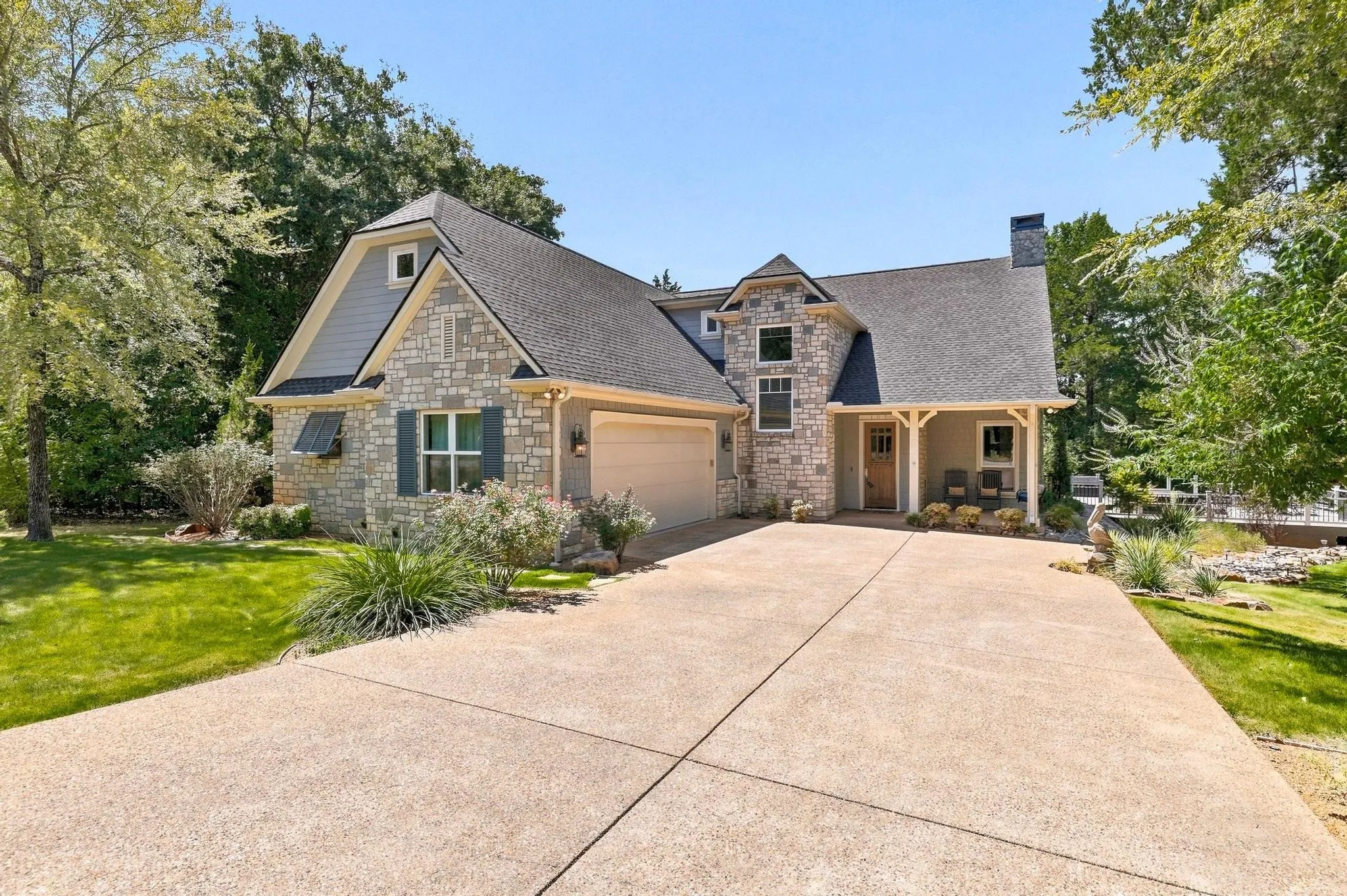 Stone and siding exterior with a dark shingle roof