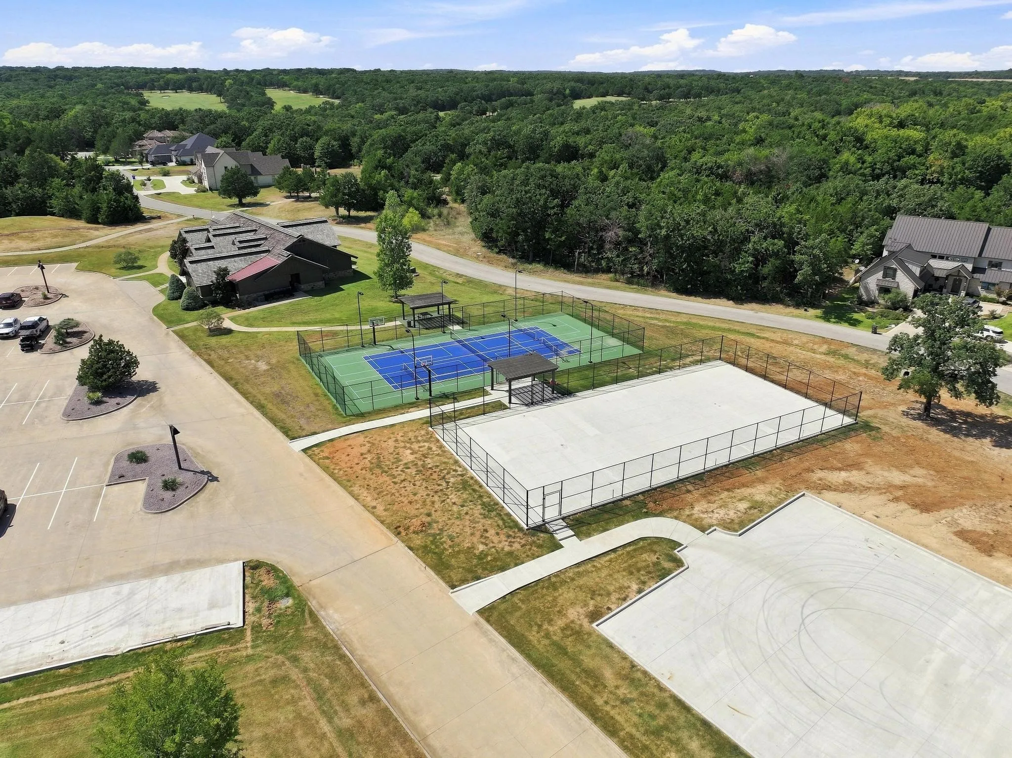 Fenced tennis court, fenced sport court, and a paved parking area