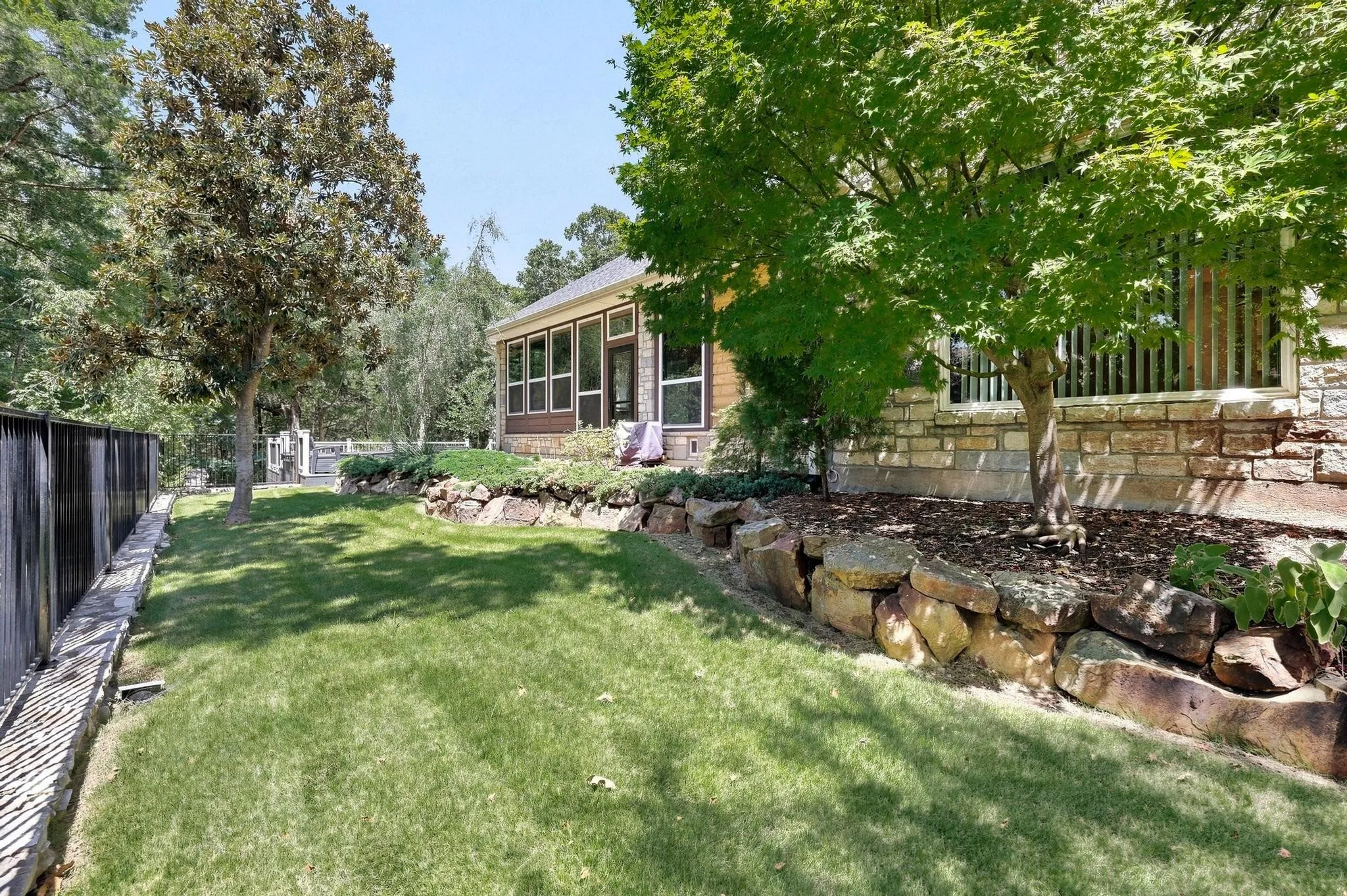 Expansive lawn area with a stone retaining wall and established trees