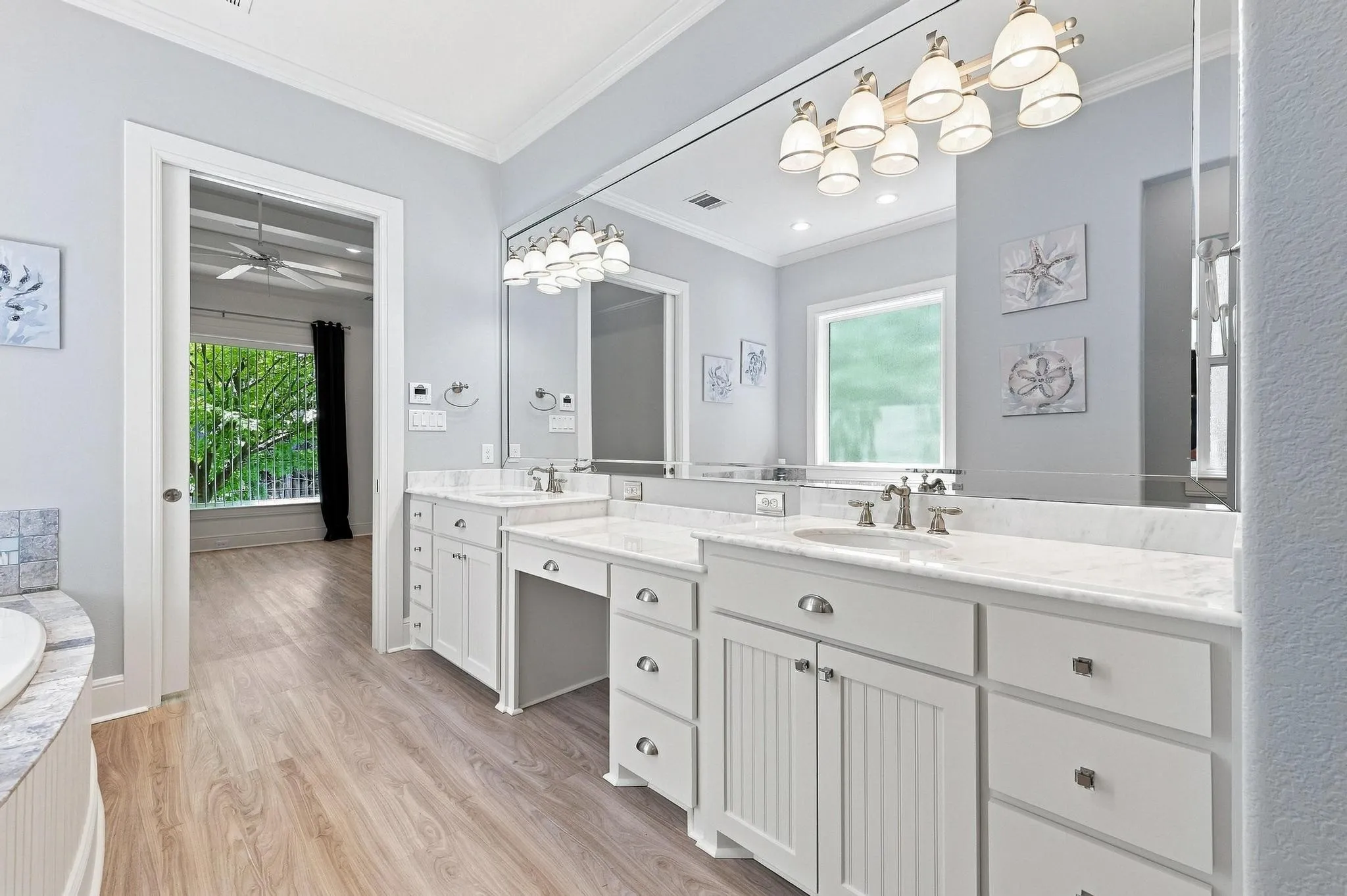 Dual vanity with integrated sinks and white countertops, wood-finish flooring, and white cabinetry