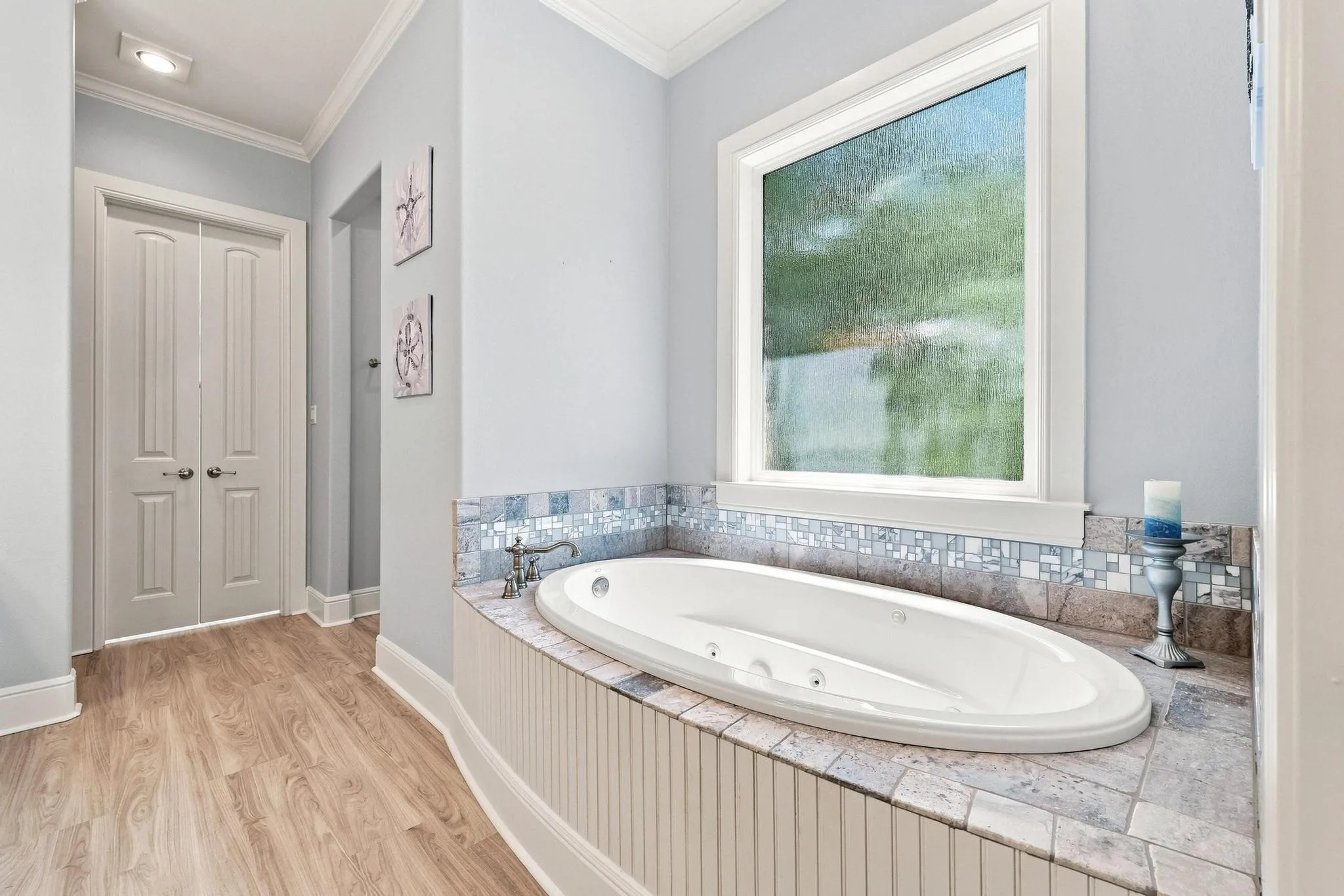 Recessed lighting, crown molding, wood-finish flooring, built-in soaking tub with tile surround, and a frosted window