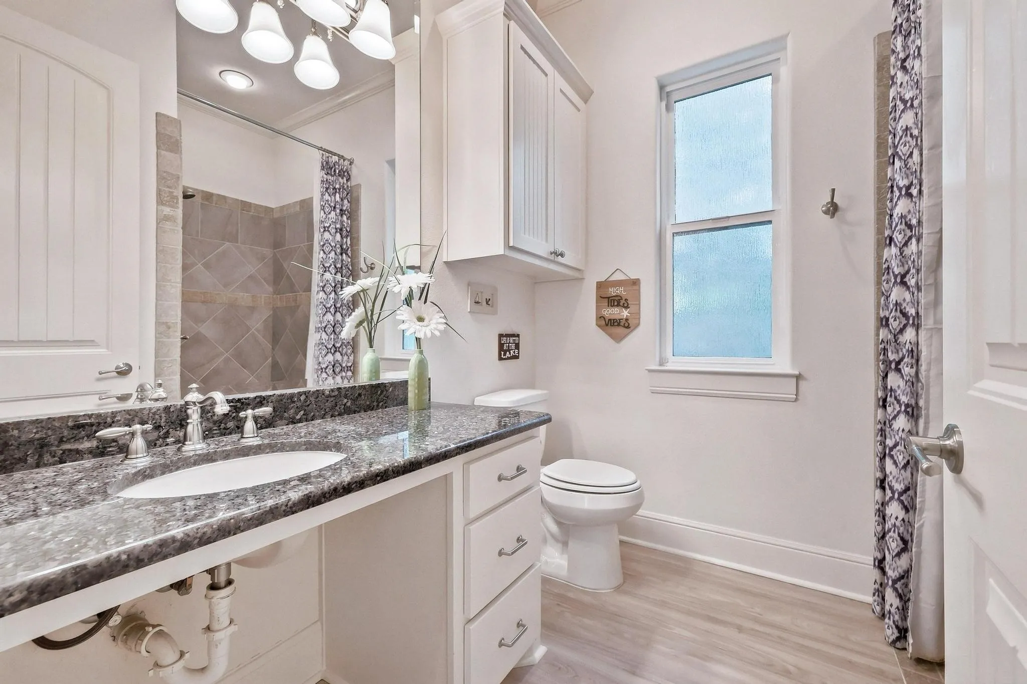 Vanity with a polished stone countertop, undermount sink, and brushed nickel fixtures