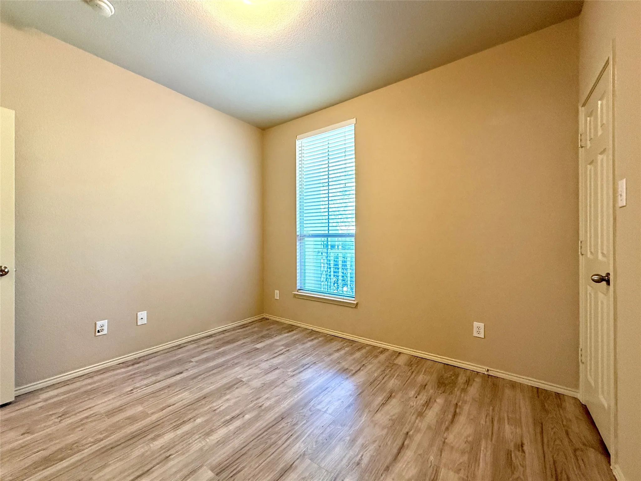 Wood-finish flooring throughout, neutral tone walls, and a window with blinds