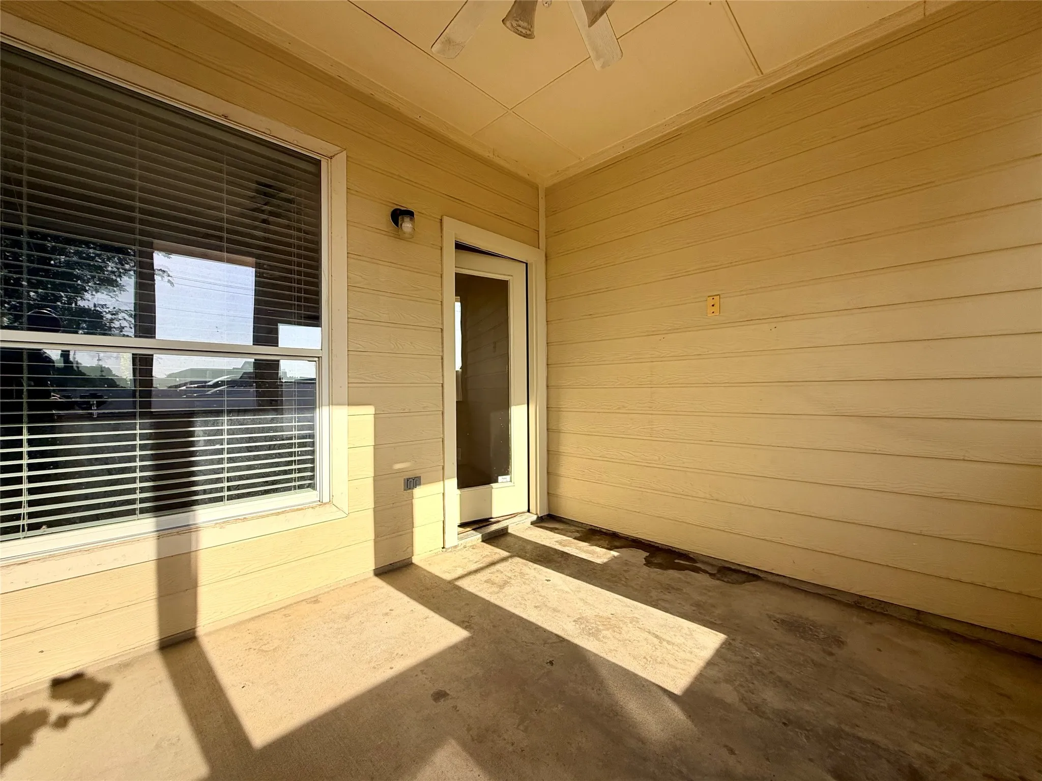 Covered patio featuring a concrete floor, exterior siding, and a ceiling fan