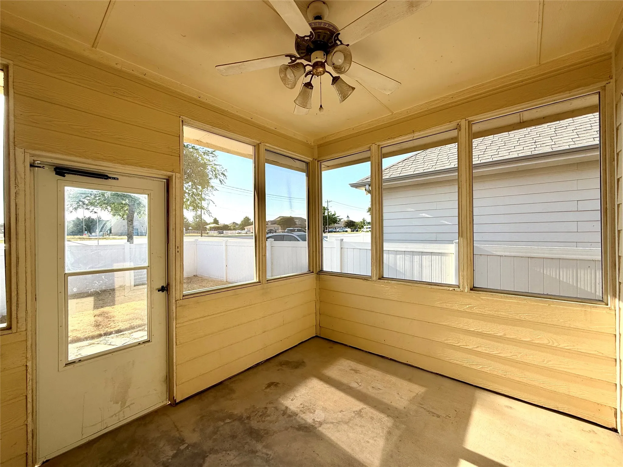Enclosed patio with full-height windows, a ceiling fan with integrated lighting, and a solid exterior door