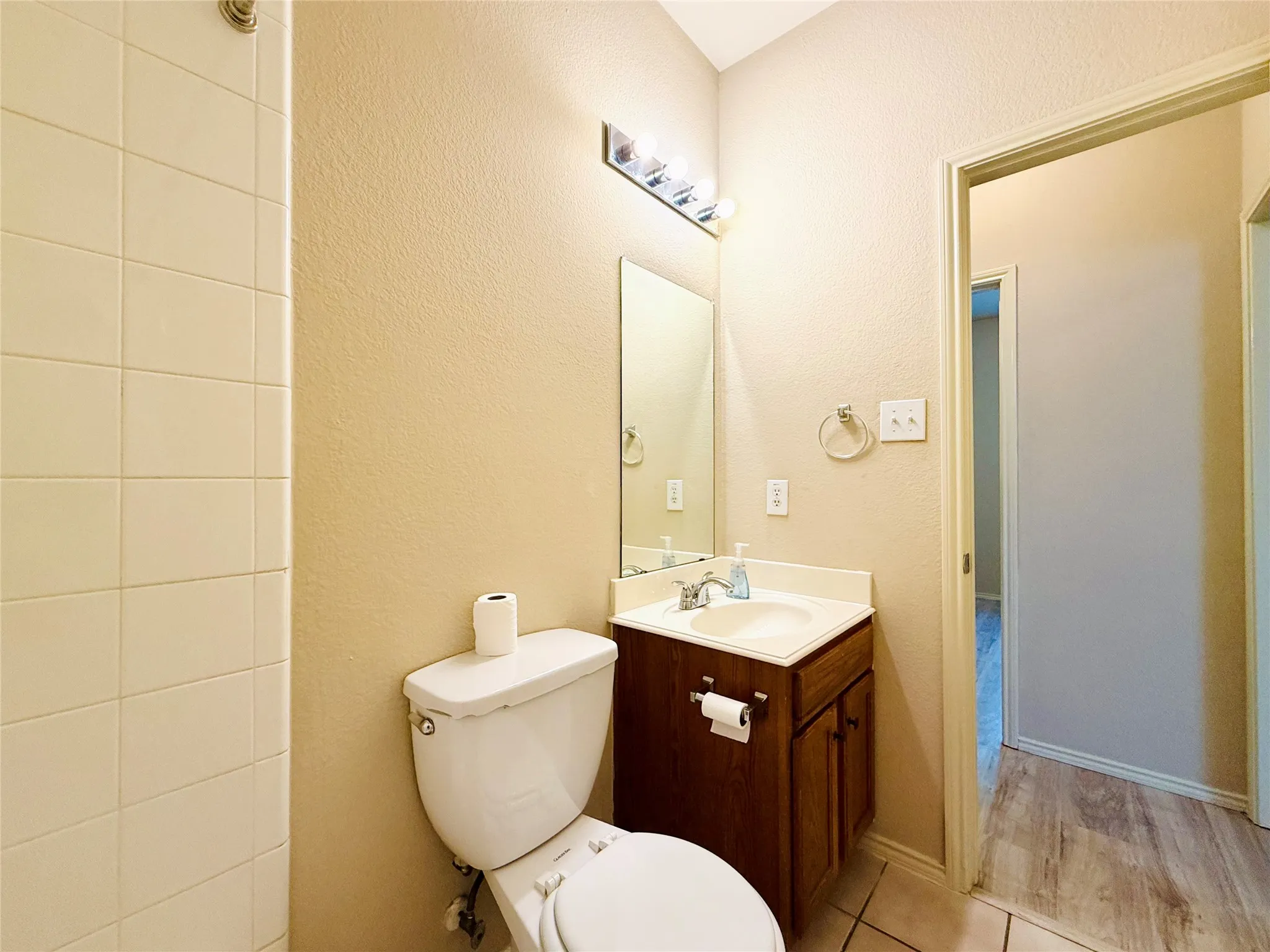 Vanity with integrated sink, wood-finish cabinetry, chrome faucet, and overhead vanity lighting