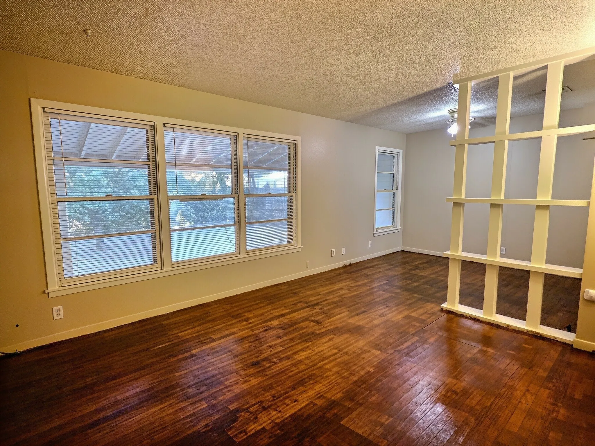 Hardwood-finish flooring, multiple windows, and a decorative room divider