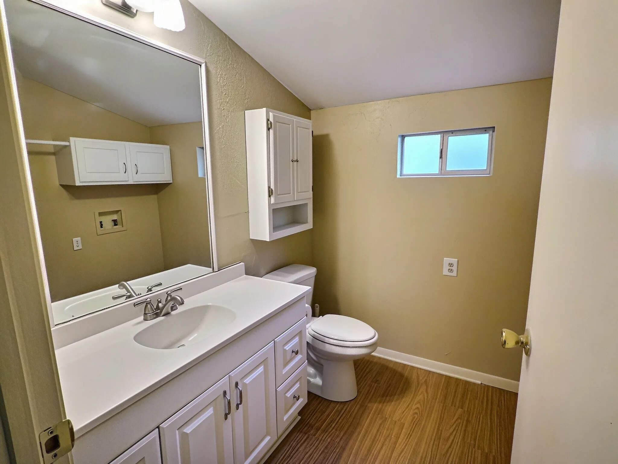 White vanity with integrated sink, wood-finish flooring, and wall-mounted cabinetry