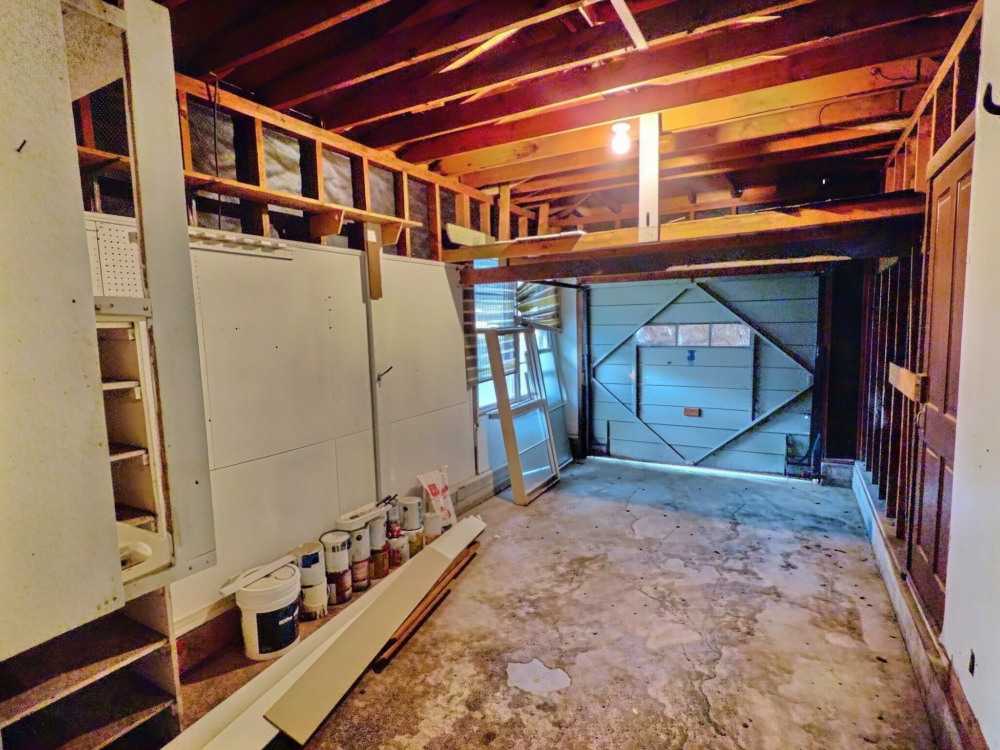 Exposed wood beam ceiling, concrete flooring, built-in shelving, paneled accent wall, and garage door