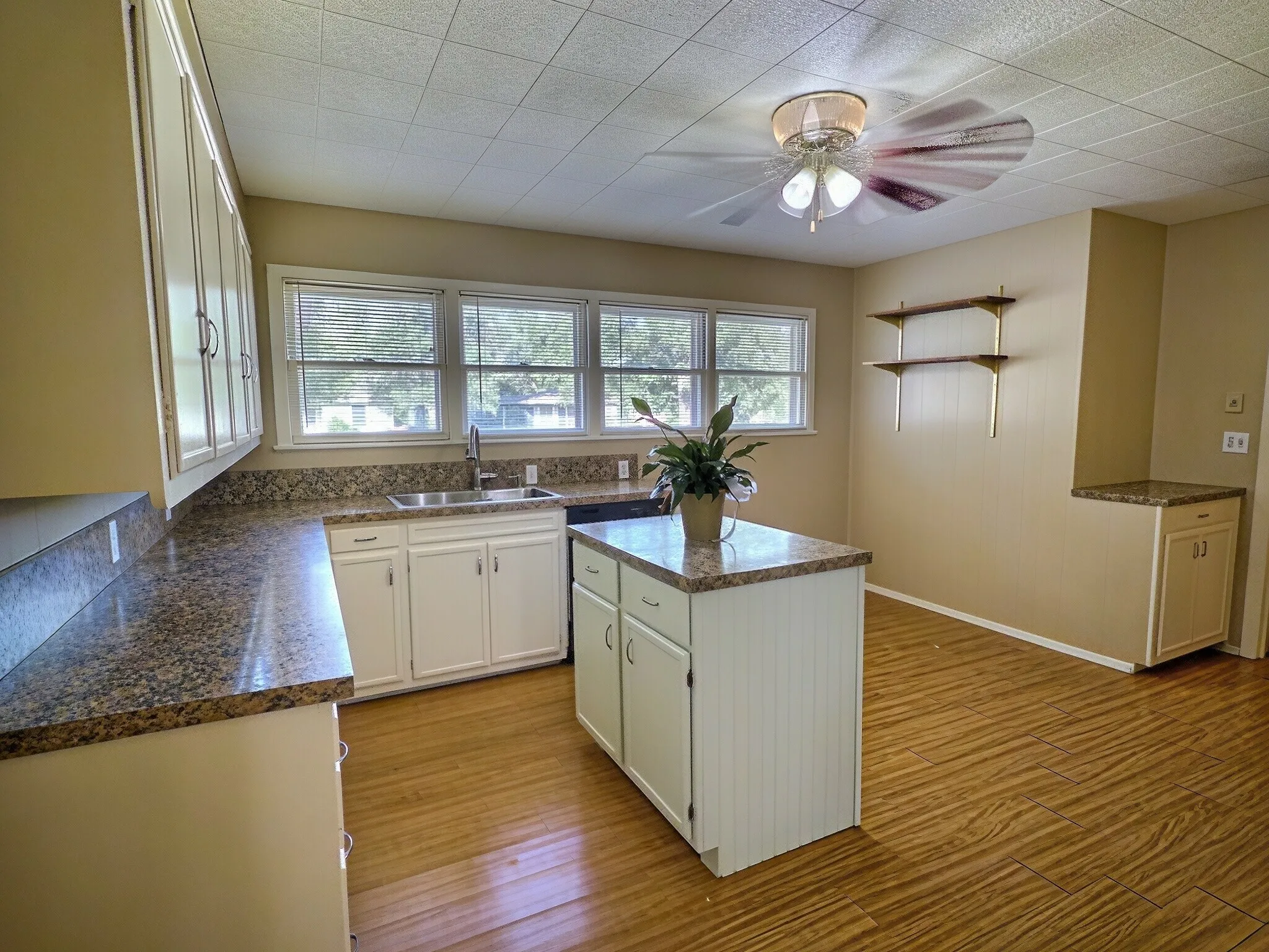 Kitchen featuring granite-style countertops, white cabinetry, wood-finish flooring, a kitchen island, and a ceiling fan