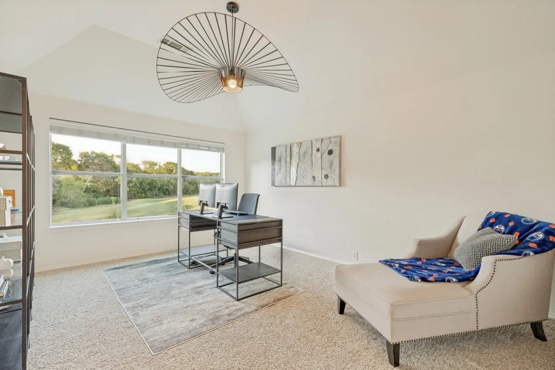 Vaulted ceiling with a sculptural light fixture, expansive windows, light-colored carpeting, and neutral wall tones