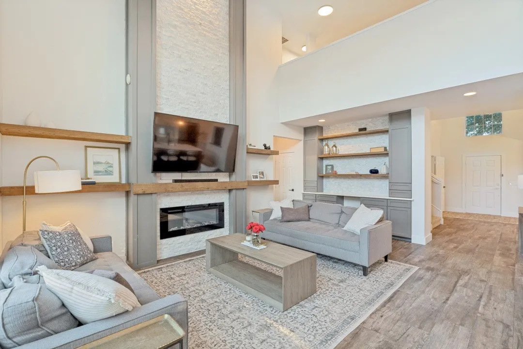 Vaulted ceiling with recessed lighting, stone-finish fireplace with hearth, built-in shelving, wood-finish flooring, and a glass block window