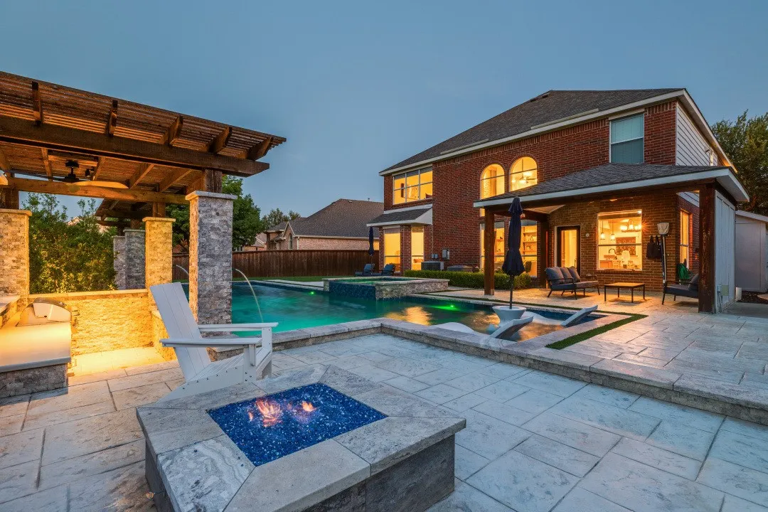 Spacious patio featuring a built-in fire pit, swimming pool with water features, and a pergola-covered outdoor kitchen