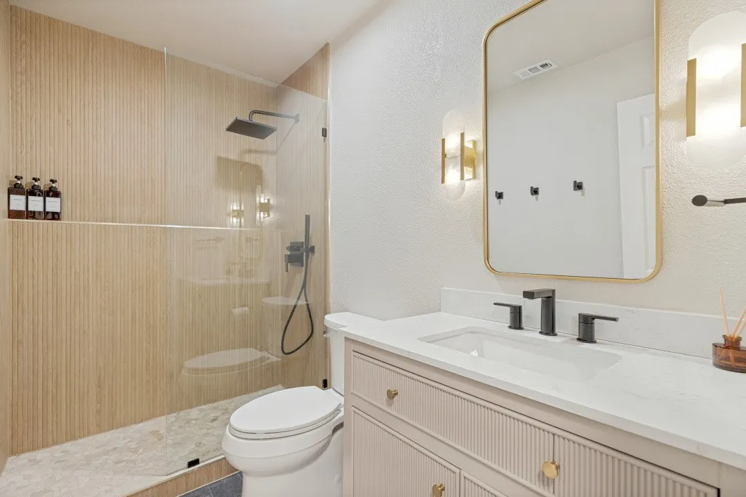 Walk-in shower with vertical wood-finish tile, glass enclosure, and rainfall showerhead