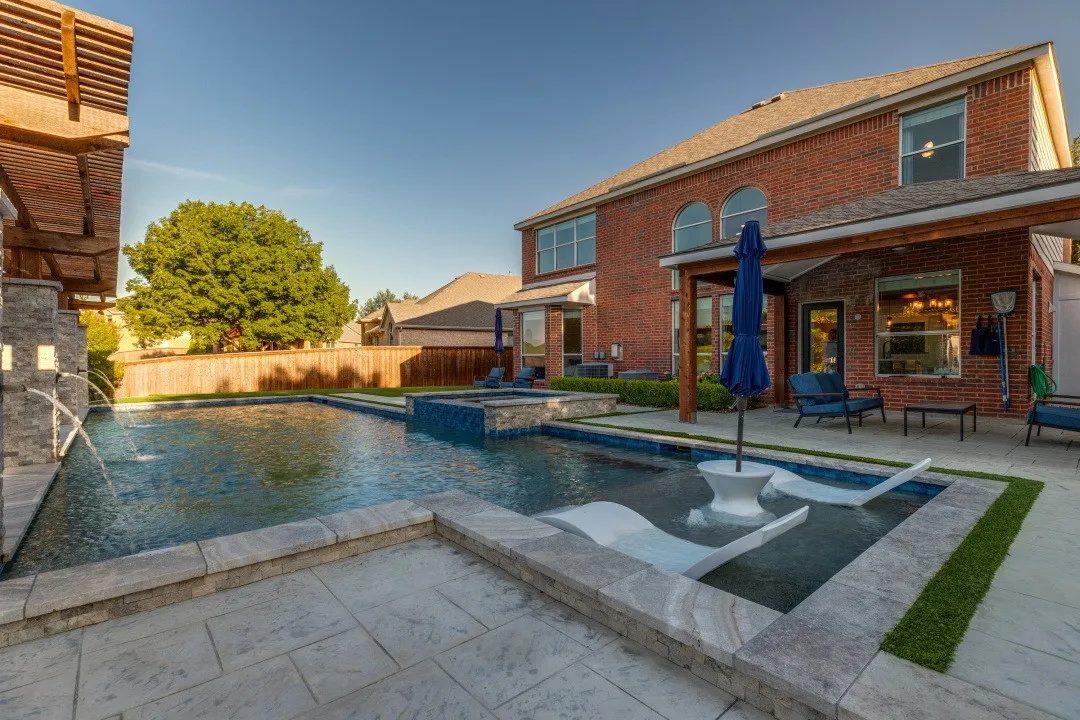 Brick exterior with an expansive pool, integrated spa, and water features