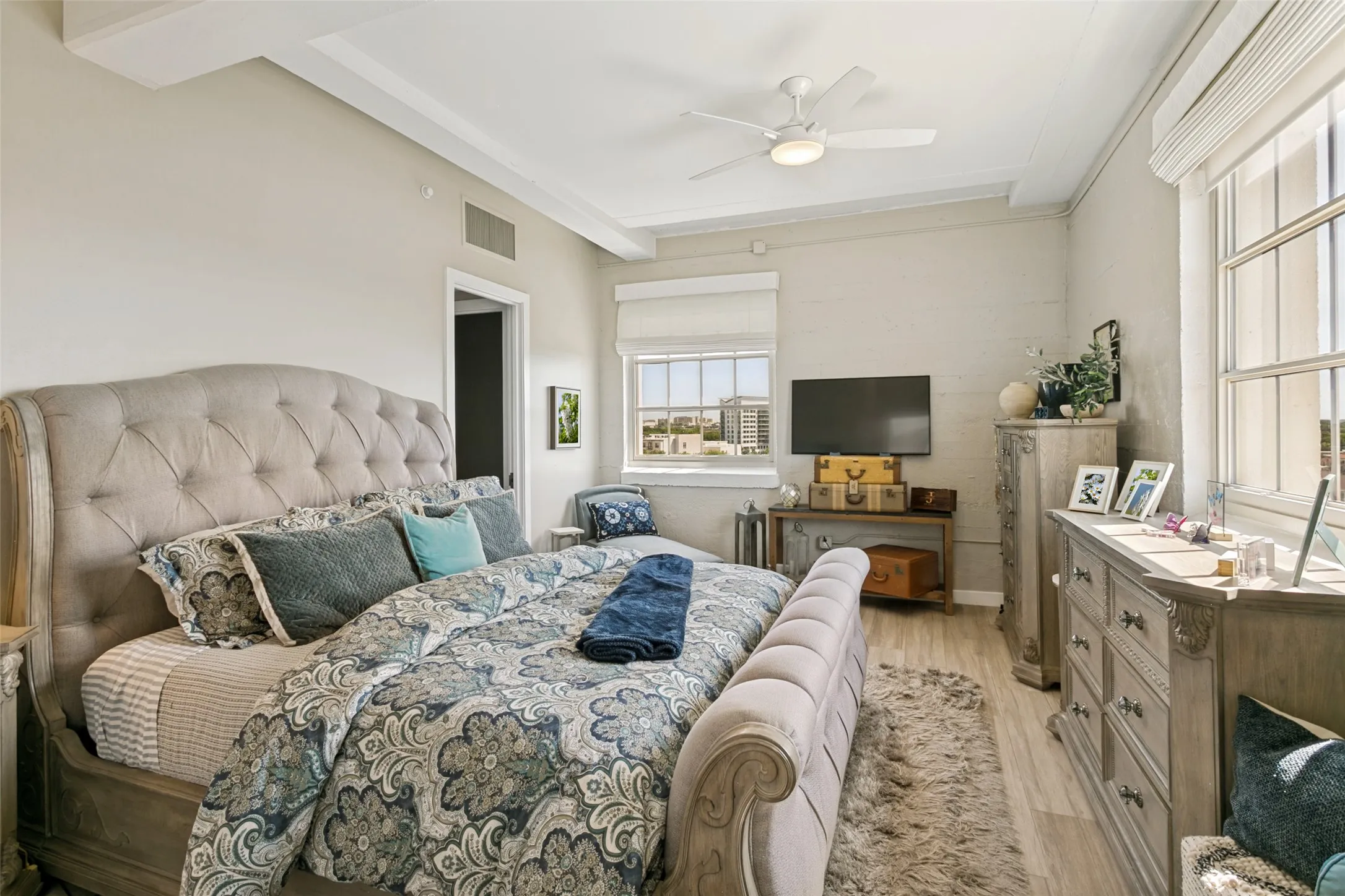Porcelain wood-look flooring with crown molding, Minka ceiling fan, and multiple windows with Roman shades