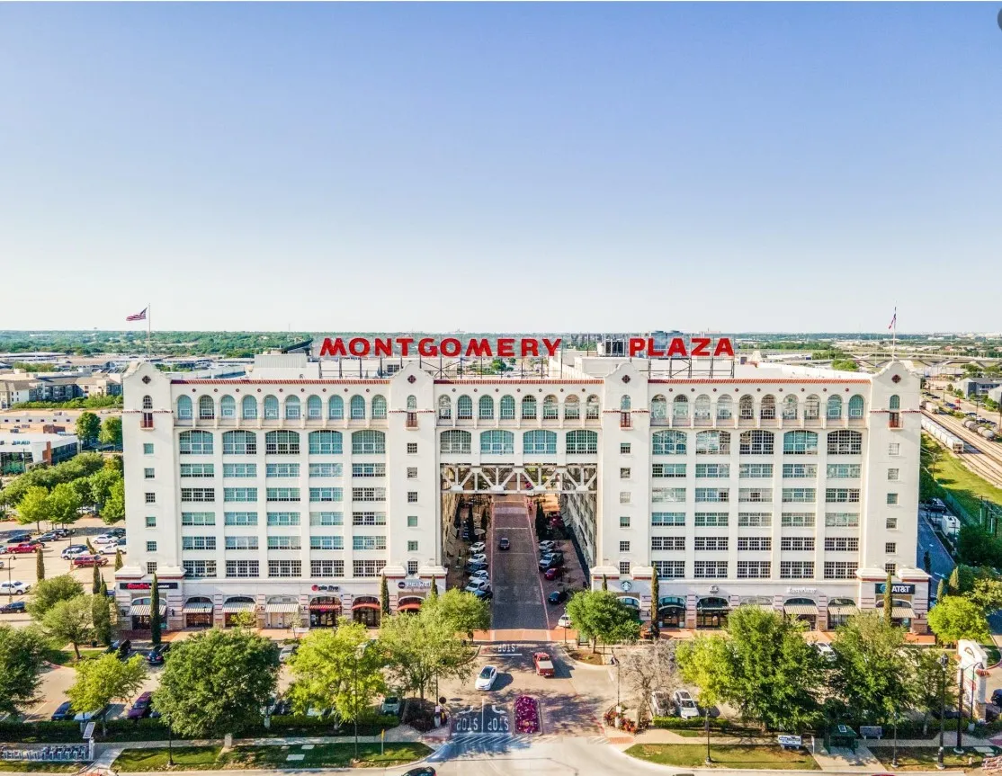 Montgomery Plaza building with a white facade, arched windows, prominent signage, and integrated parking structure