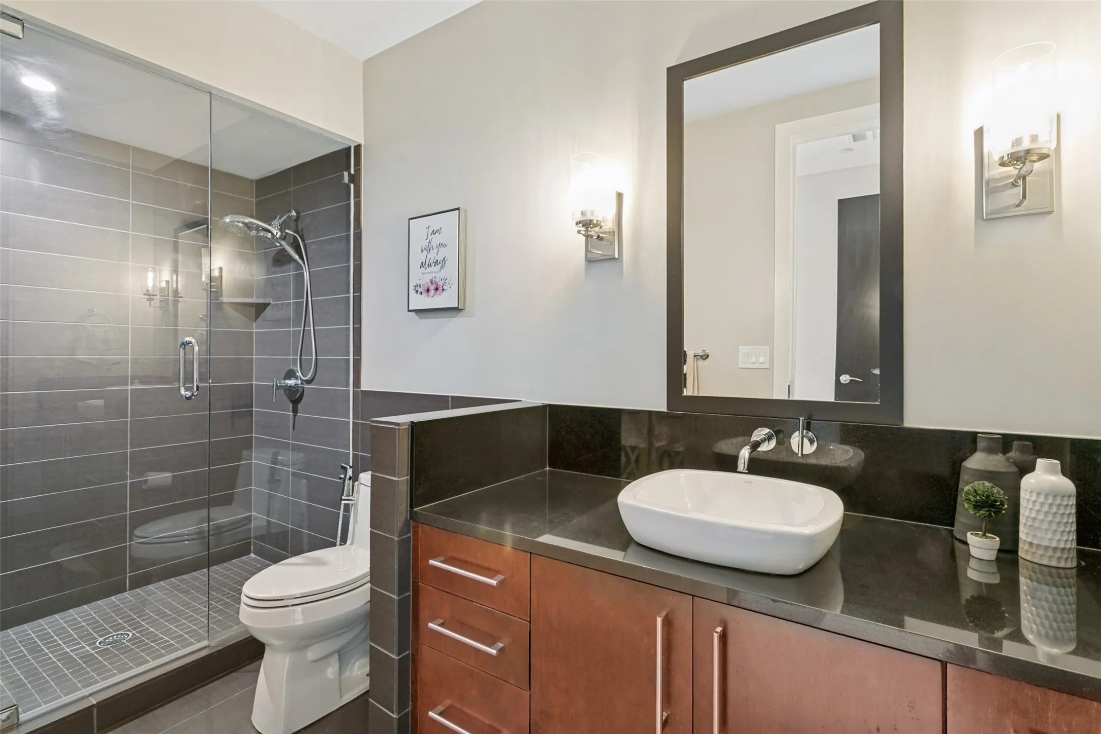 Glass-enclosed shower with dark tile surround, wall-mounted showerhead, and a built-in shelf