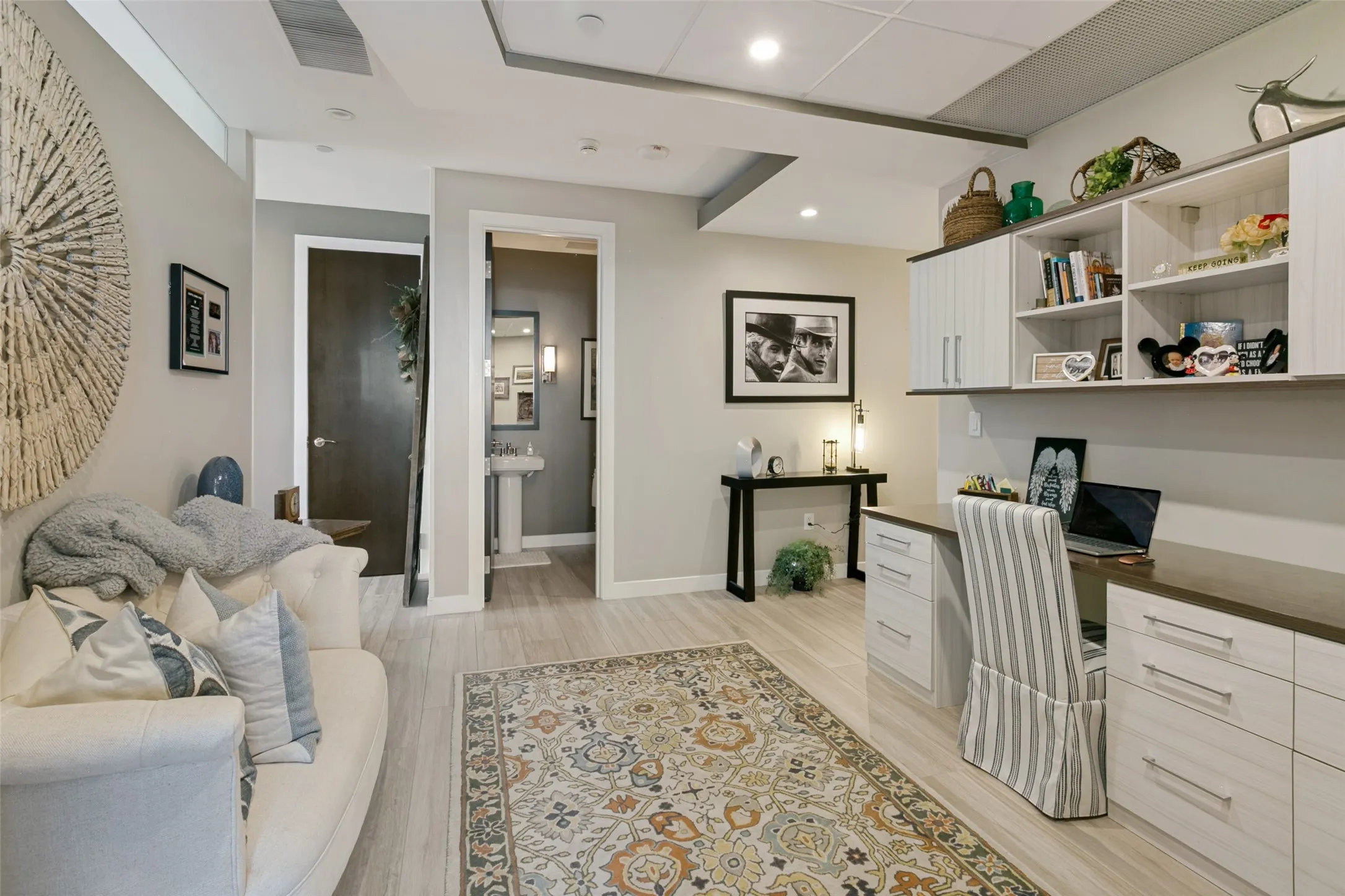 Recessed lighting, porcelain wood-look flooring, built-in desk with integrated storage, and overhead cabinetry