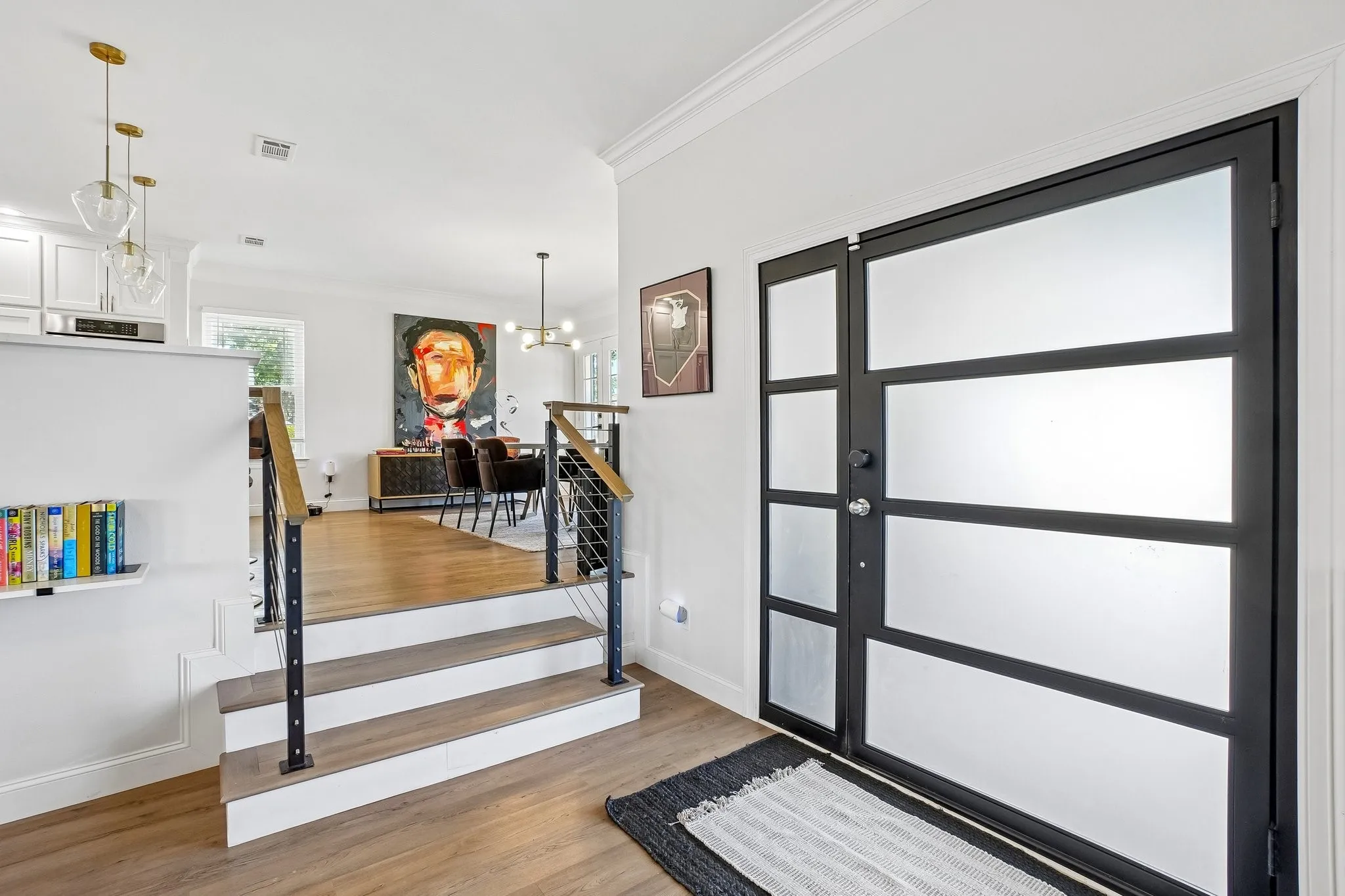 Frosted glass entry door with a sidelight, wood-finish flooring, and a contemporary stair railing with wood and metal elements