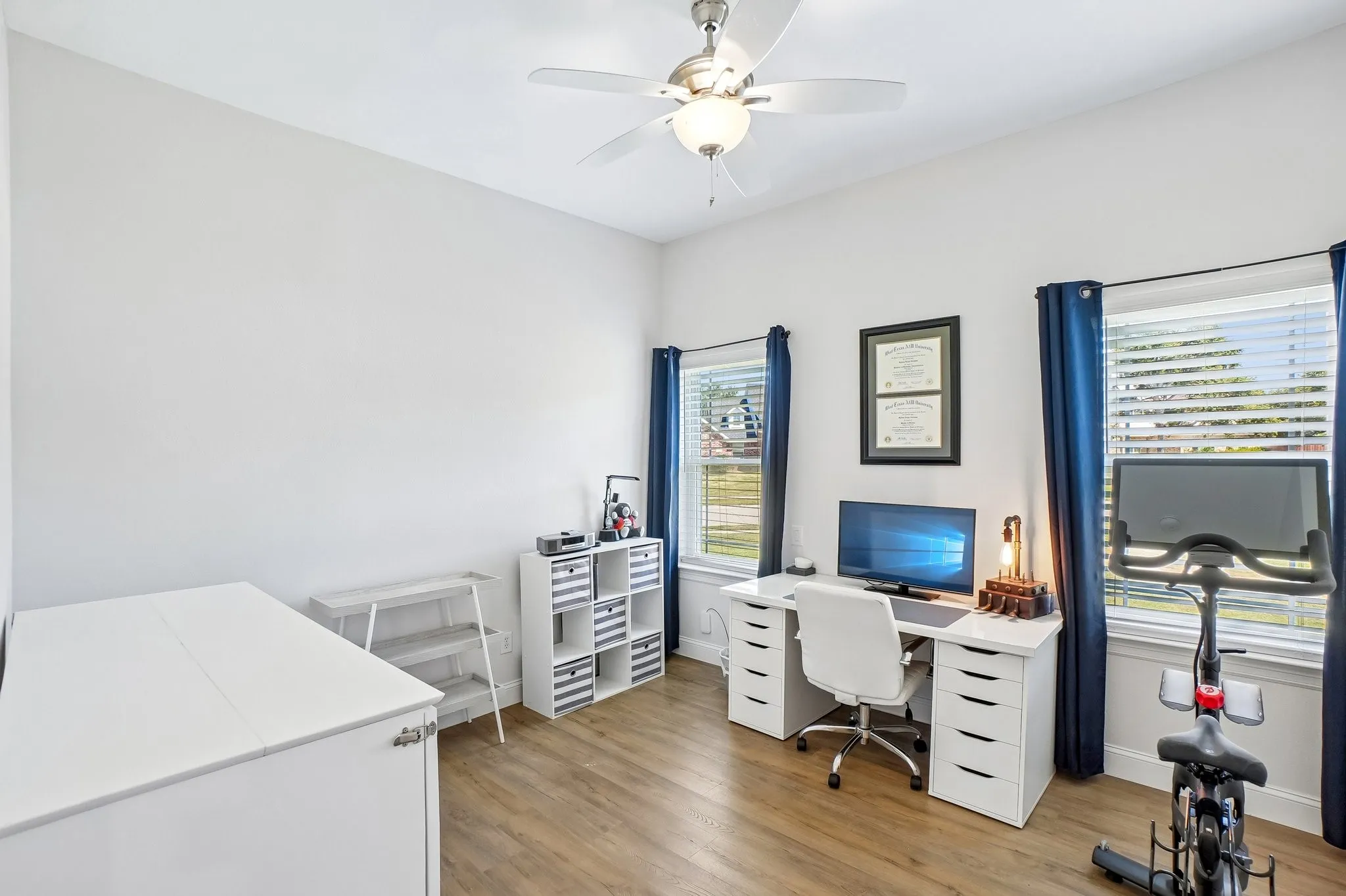 High ceilings with a ceiling fan, abundant natural light from multiple windows, and wood-finish flooring
