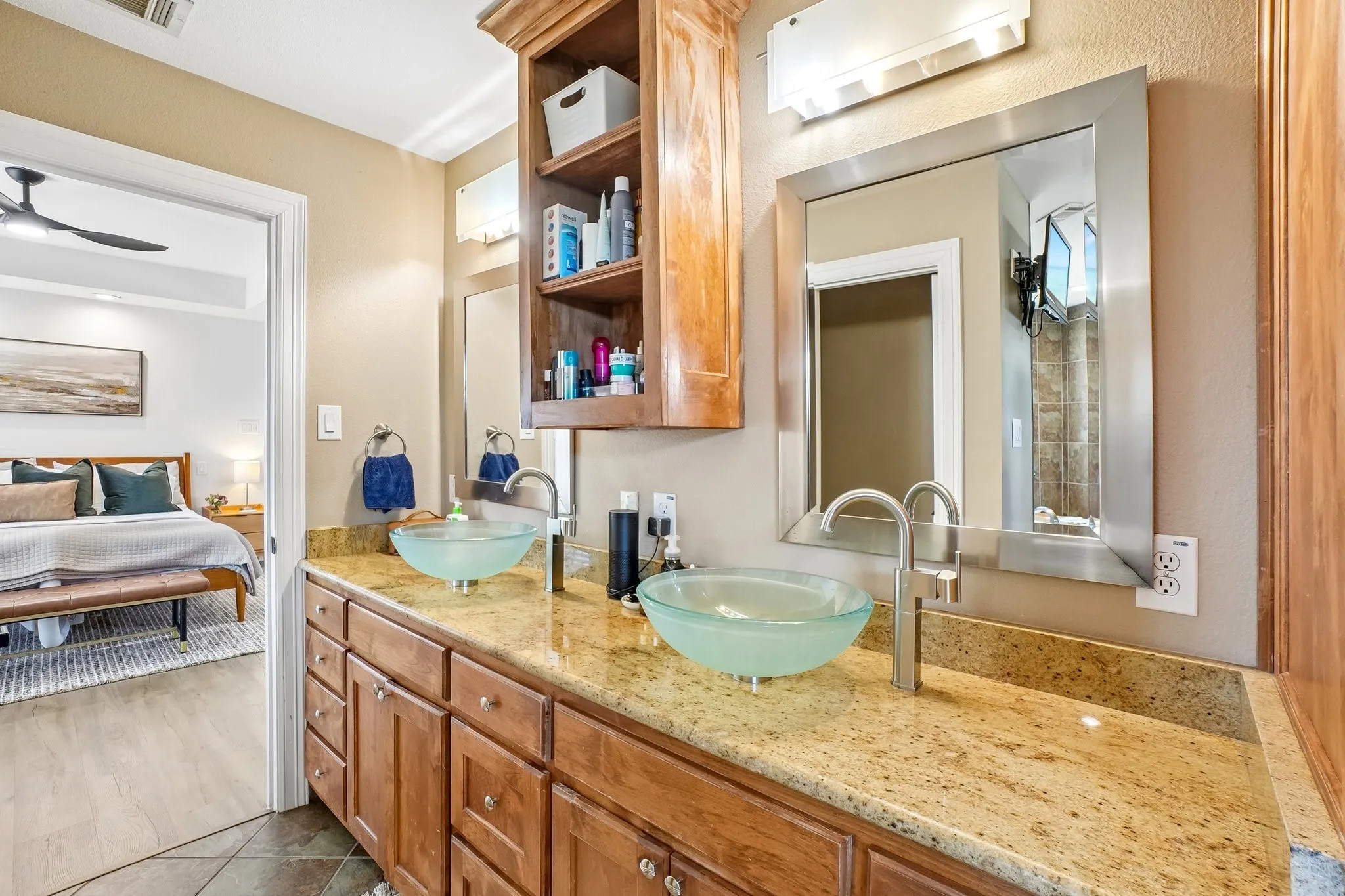 Double vanity with two vessel sinks, granite-finish countertop, wood-finish cabinetry, and framed mirrors